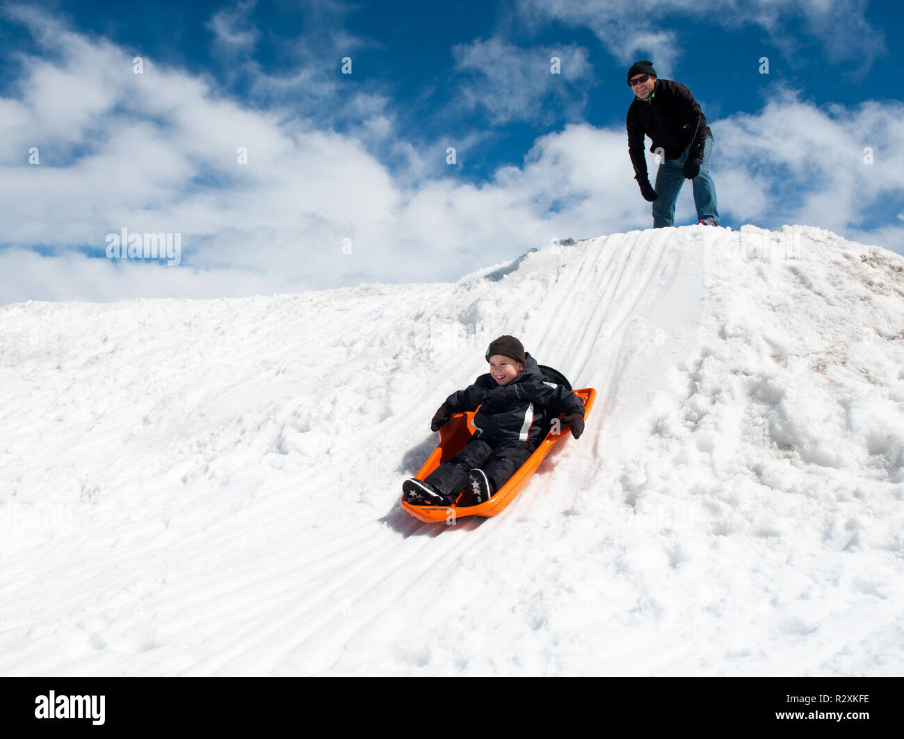 Little Boy und Papa Fahrt auf einem verschneiten Hügel. Stockfoto