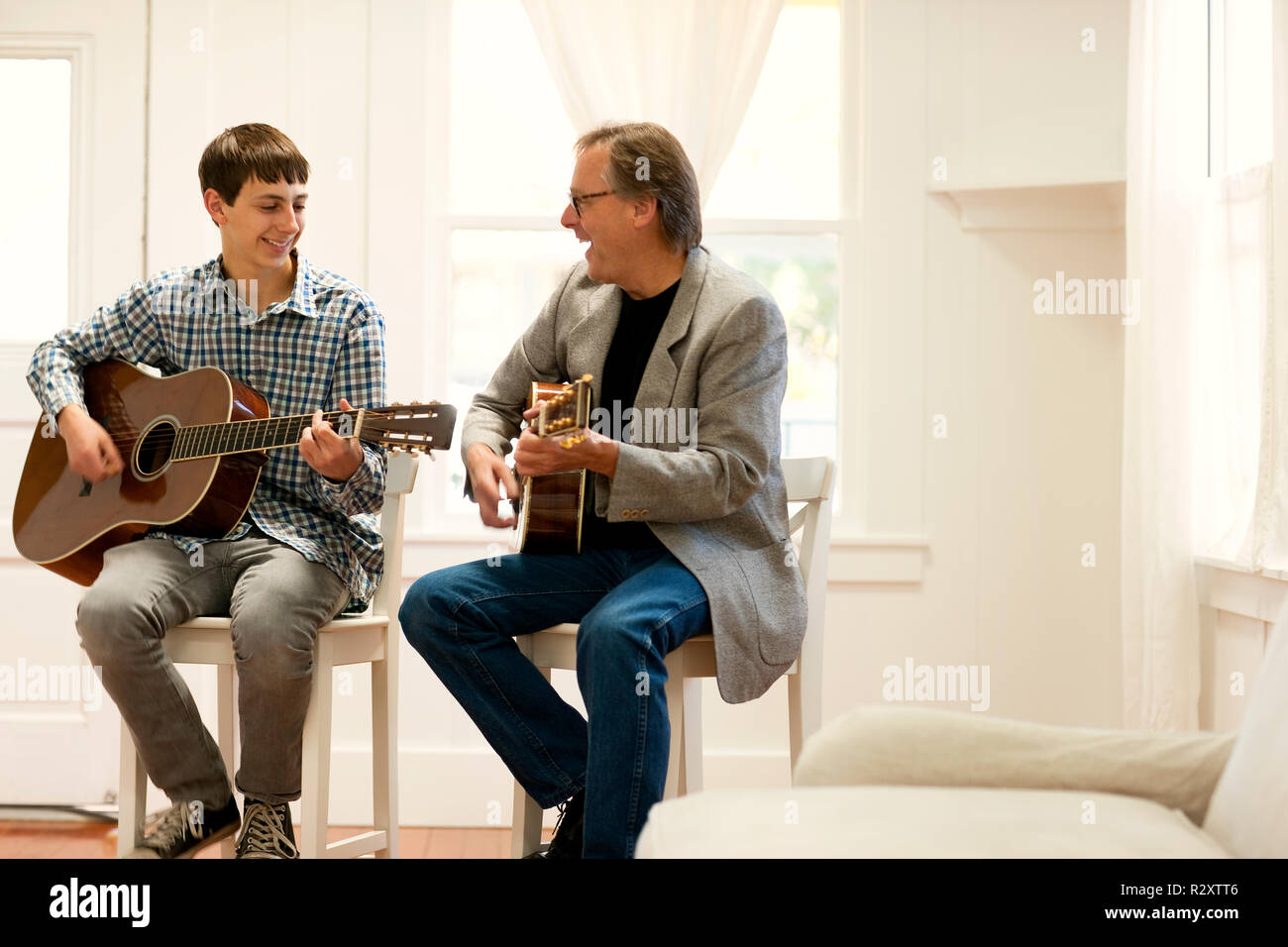 Mitte der erwachsene Mann ein Teenager beibringen, wie man Gitarre spielen. Stockfoto