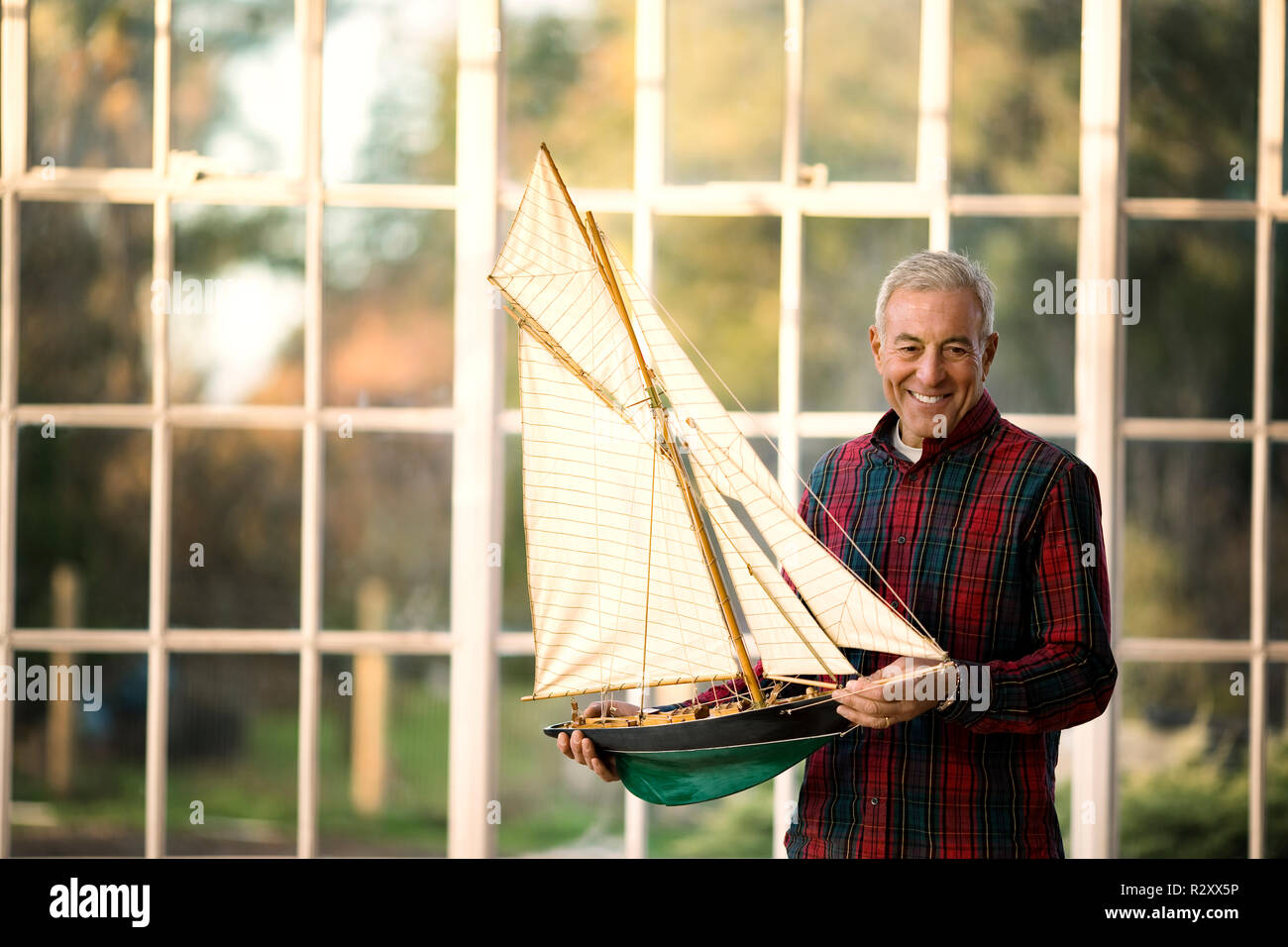 Porträt eines lächelnden älteren Mann hält ein Modell Boot. Stockfoto