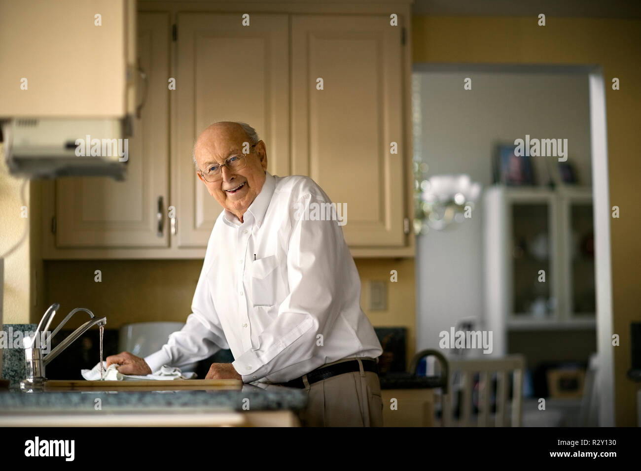 Lächelnd älterer Mann reinigt bis in die Küche nach dem Mittagessen. Stockfoto