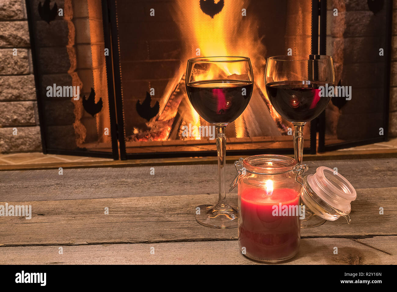 Ruhige Szene vor dem gemütlichen Kamin, mit zwei Gläsern Rotwein und Kerzenlicht, in Country House, im Winter Urlaub. Stockfoto