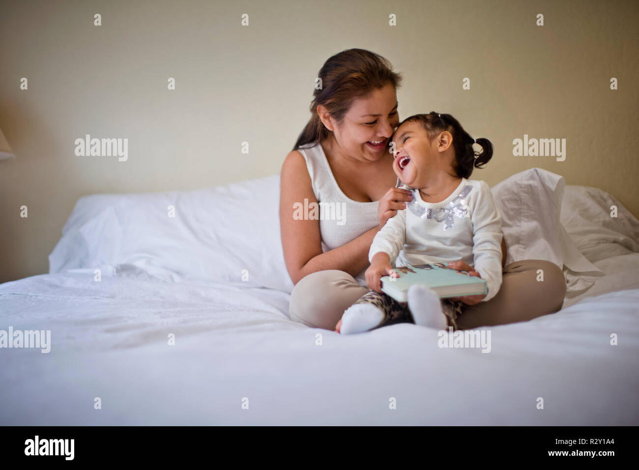 Glückliche junge Mutter spielerisch kitzeln Ihren Toddler Tochter. Stockfoto