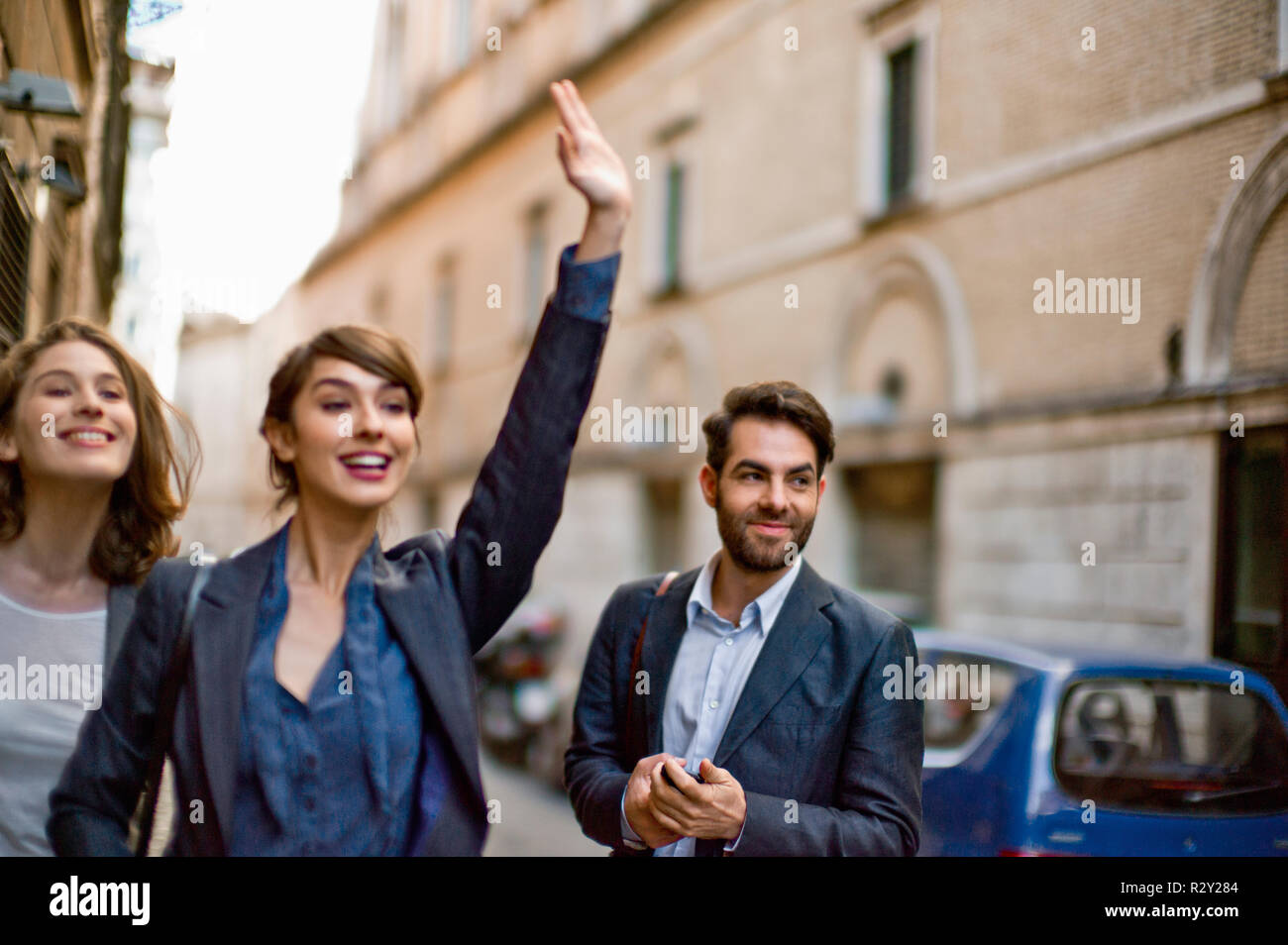 Lächelnden jungen Geschäftsfrau hageln ein Taxi für Ihre Kollegen. Stockfoto