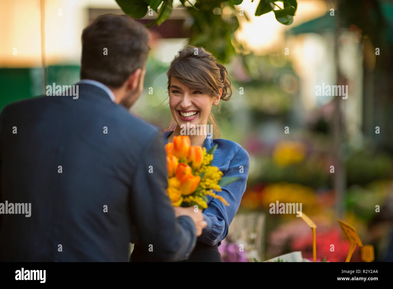 Junge Unternehmer präsentiert seine Kollegen mit einem Bündel von Tulpen in einem Blumenmarkt. Stockfoto