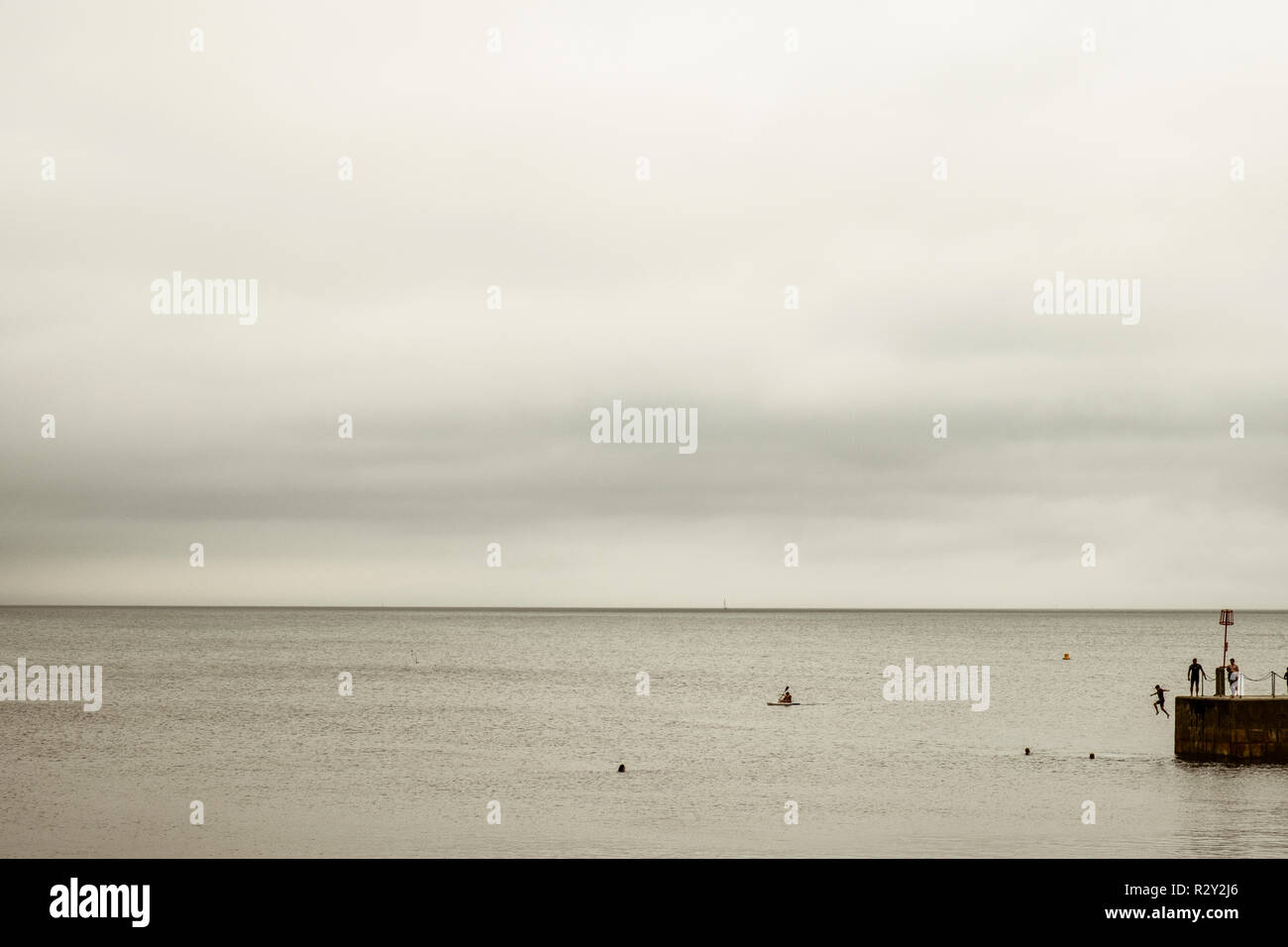 Blick auf das Meer und die Menschen schwimmen und Springen die Hafenmauer. Stockfoto