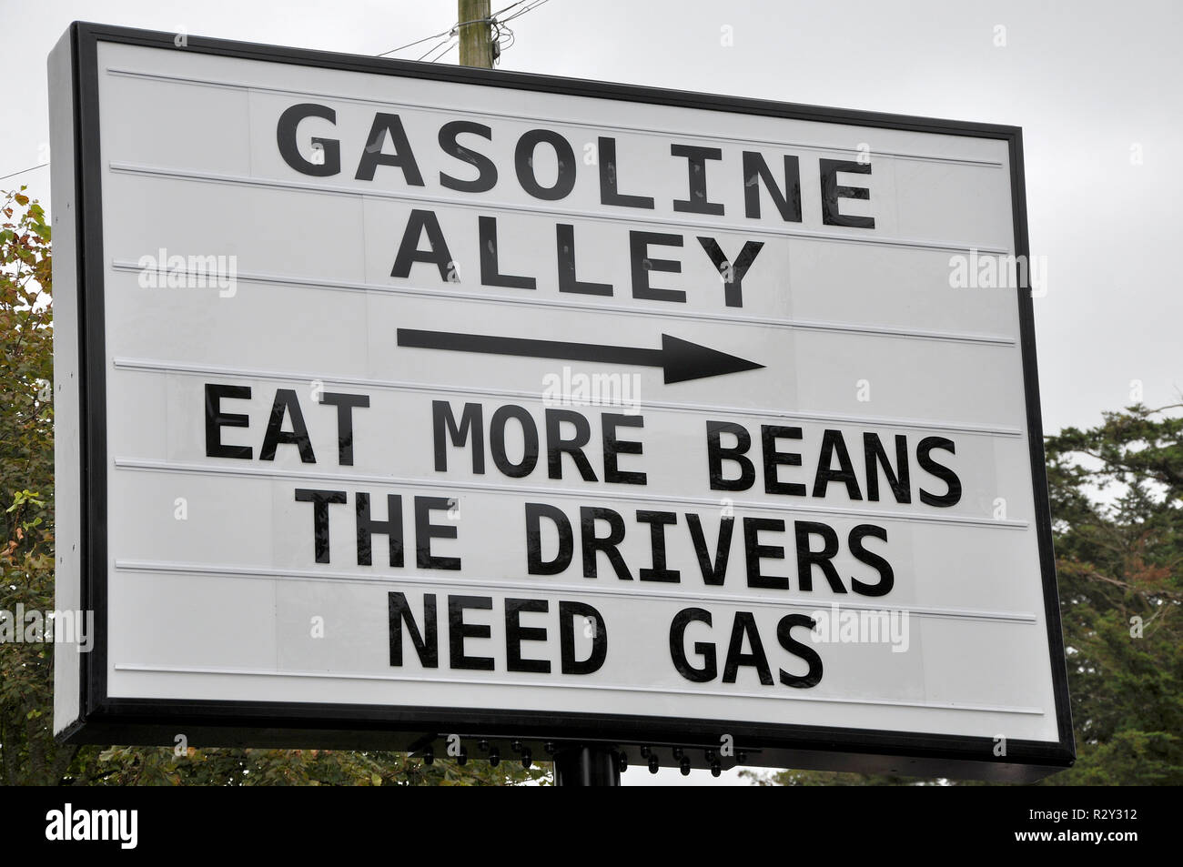 Das humorvolle Zeichen der Benzingasse beim Goodwood Revival. Essen Sie mehr Bohnen, die Fahrer brauchen Benzin. Flatulenz. Wind Stockfoto