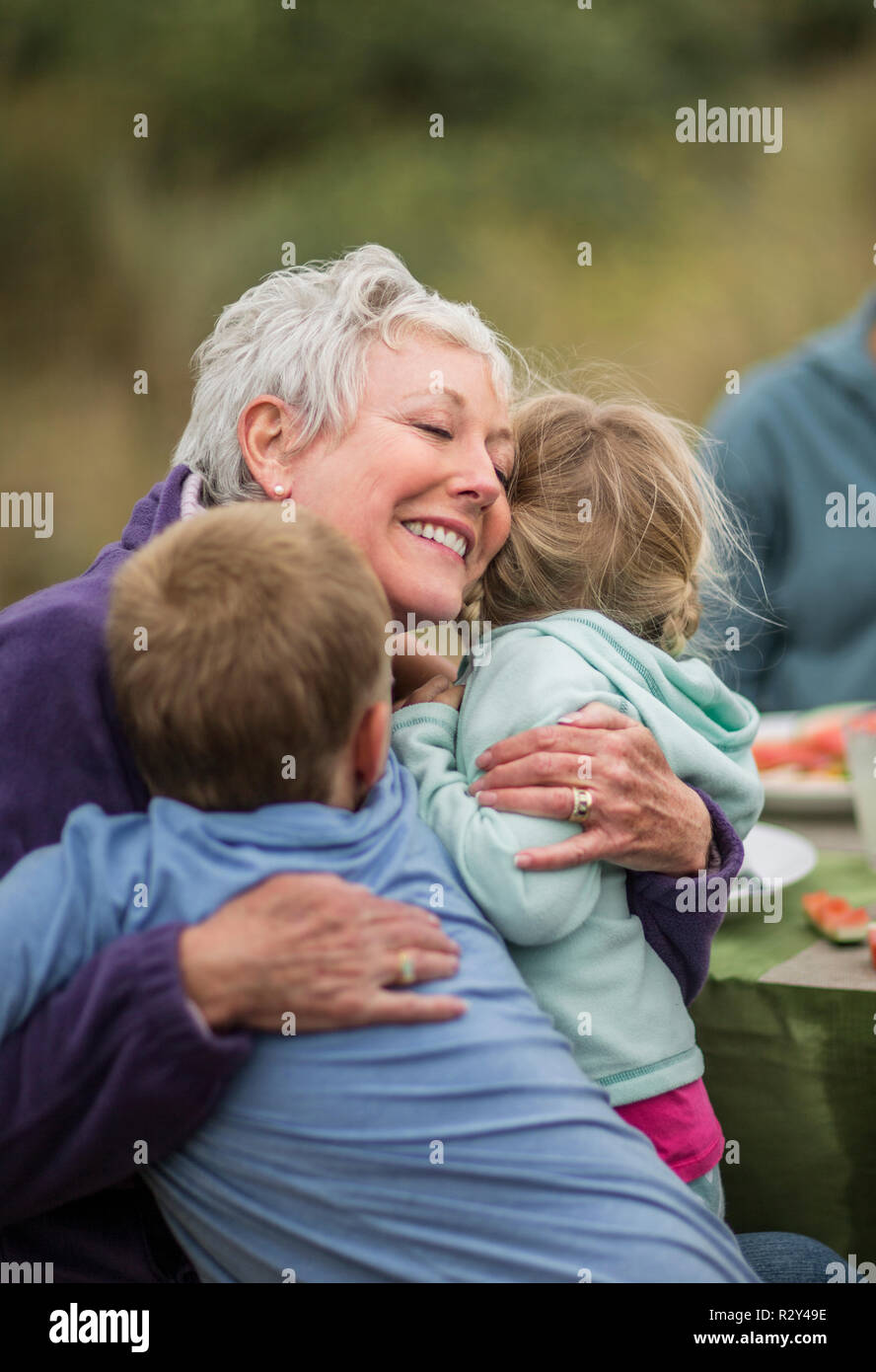 Liebevolle Großmutter umarmt sie Enkelkinder. Stockfoto