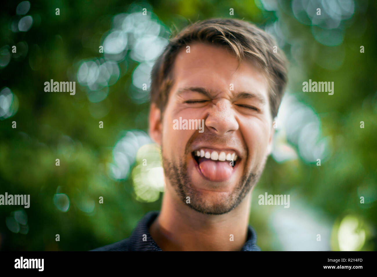 Glückliche junge Menschen ziehen ein Gesicht und seine Zunge heraus haften. Stockfoto