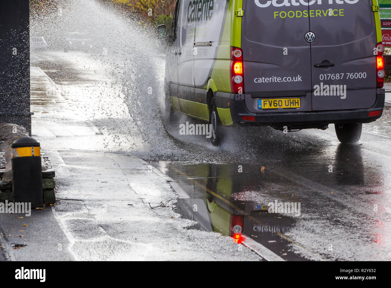 Autofahrer zu schnell gefahren durch grosse Pfützen einweichen Fußgänger und Unterkunft in Ambleside, Cumbria, Großbritannien. Stockfoto