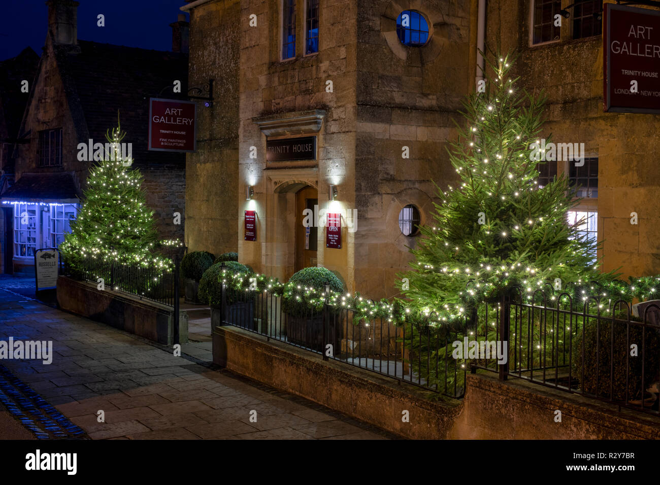 Weihnachtsbäume mit Lichtern in der Nacht außerhalb Trinty Haus Galerie in Broadway Cotswolds, Worcestershire, England Stockfoto