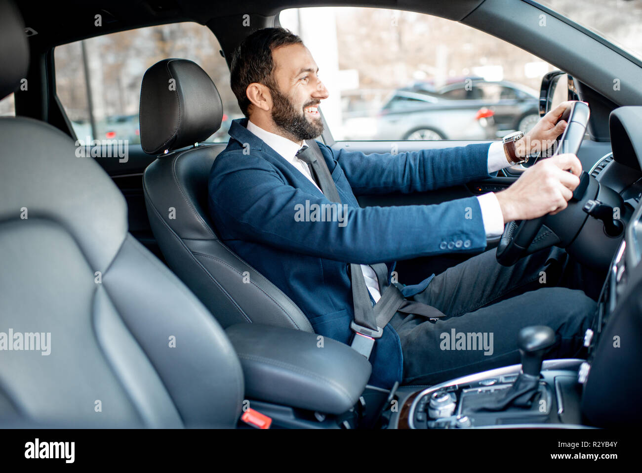 Schöne bärtige Geschäftsmann im Anzug, der ein Auto fährt in der Stadt angezogen Stockfoto