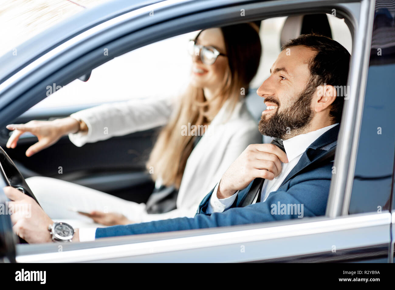 Elegante Geschäftsmann Anziehen der Riegel während der Fahrt ein Auto mit geschäftsfrau Stockfoto