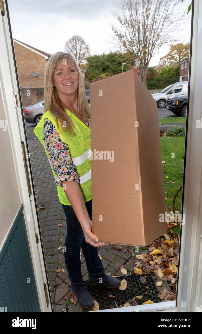 Frau Kurier Pakete zu einem Eingangstür eines Kunden nach Hause liefern Stockfoto
