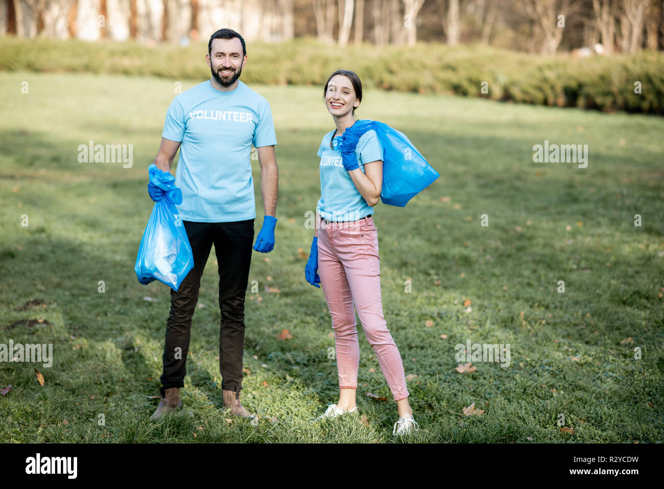 Portrait Of Happy Freiwillige in blauen T-Shirts mit Taschen voller Müll nach dem Park Reinigung Stockfoto