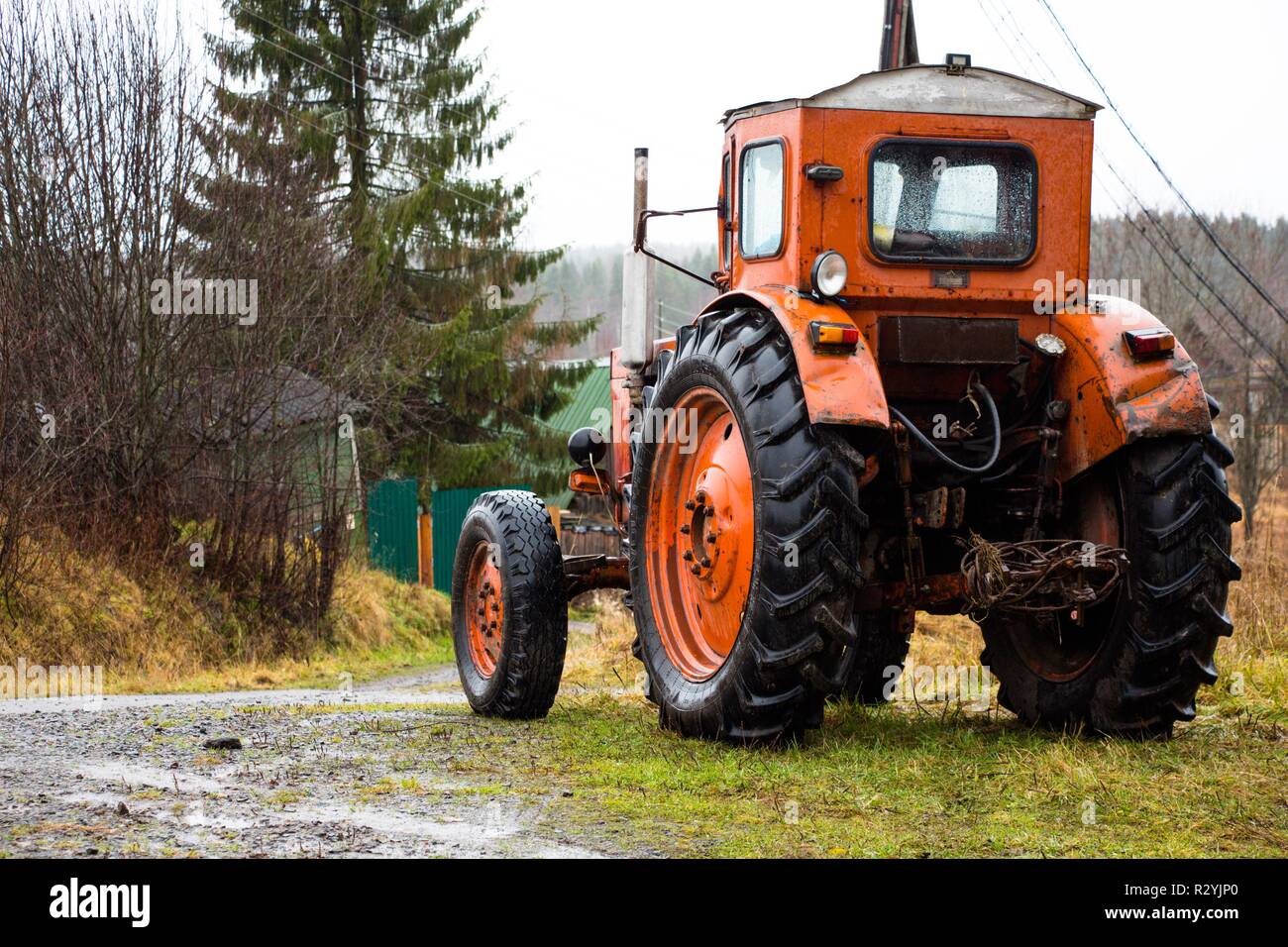 Ein Roter Traktor mit großen Rädern steht auf einem Berg in der Landschaft. Der Traktor ist bereit, im Feld und auf dem Hof zu arbeiten. Stockfoto