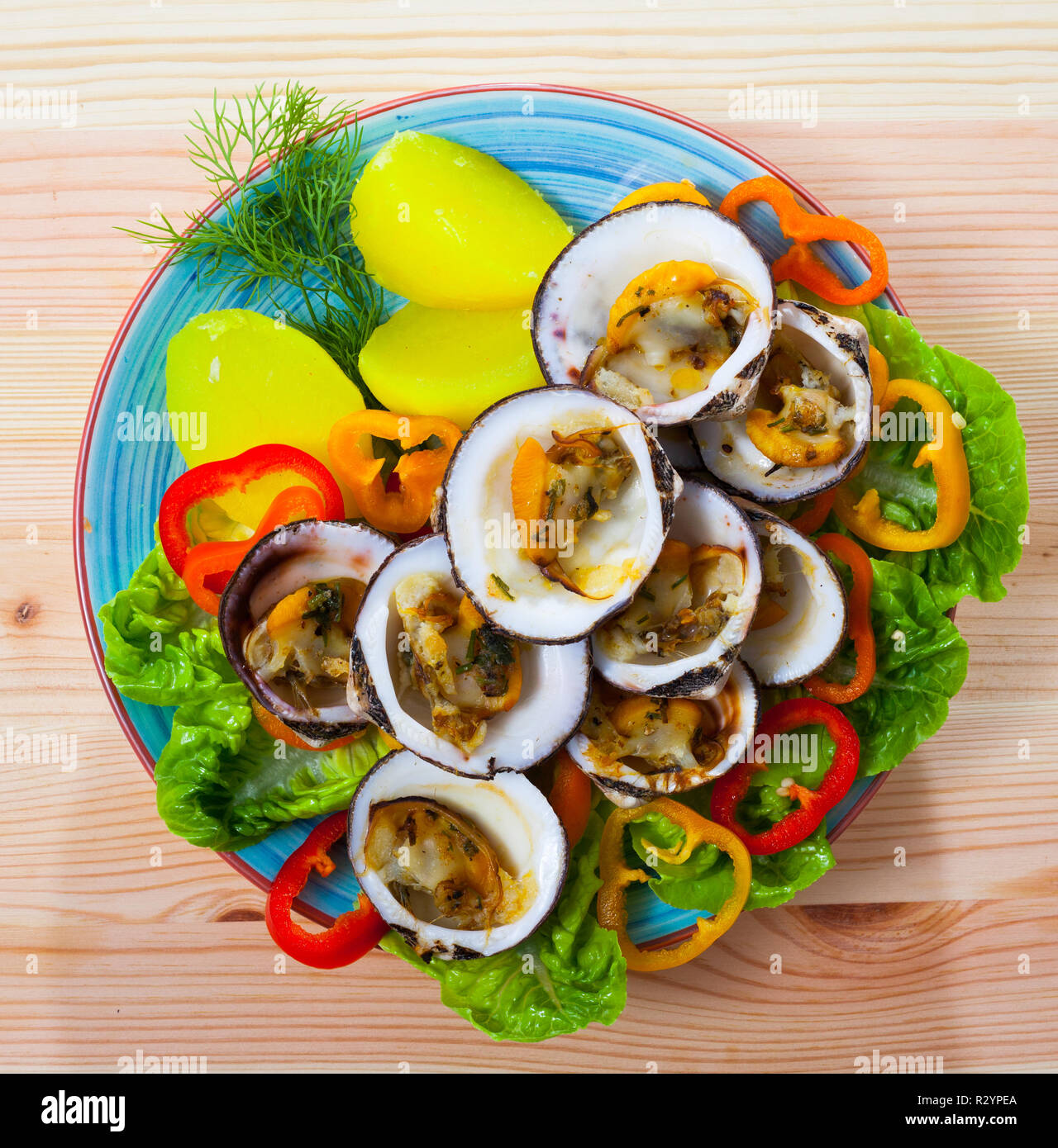 Blick von oben auf die Gebackenen im Ofen Europäischen bittersüße Muscheln mit gekochten Kartoffeln, frisches Gemüse und Grüns auf Holz- Hintergrund Stockfoto