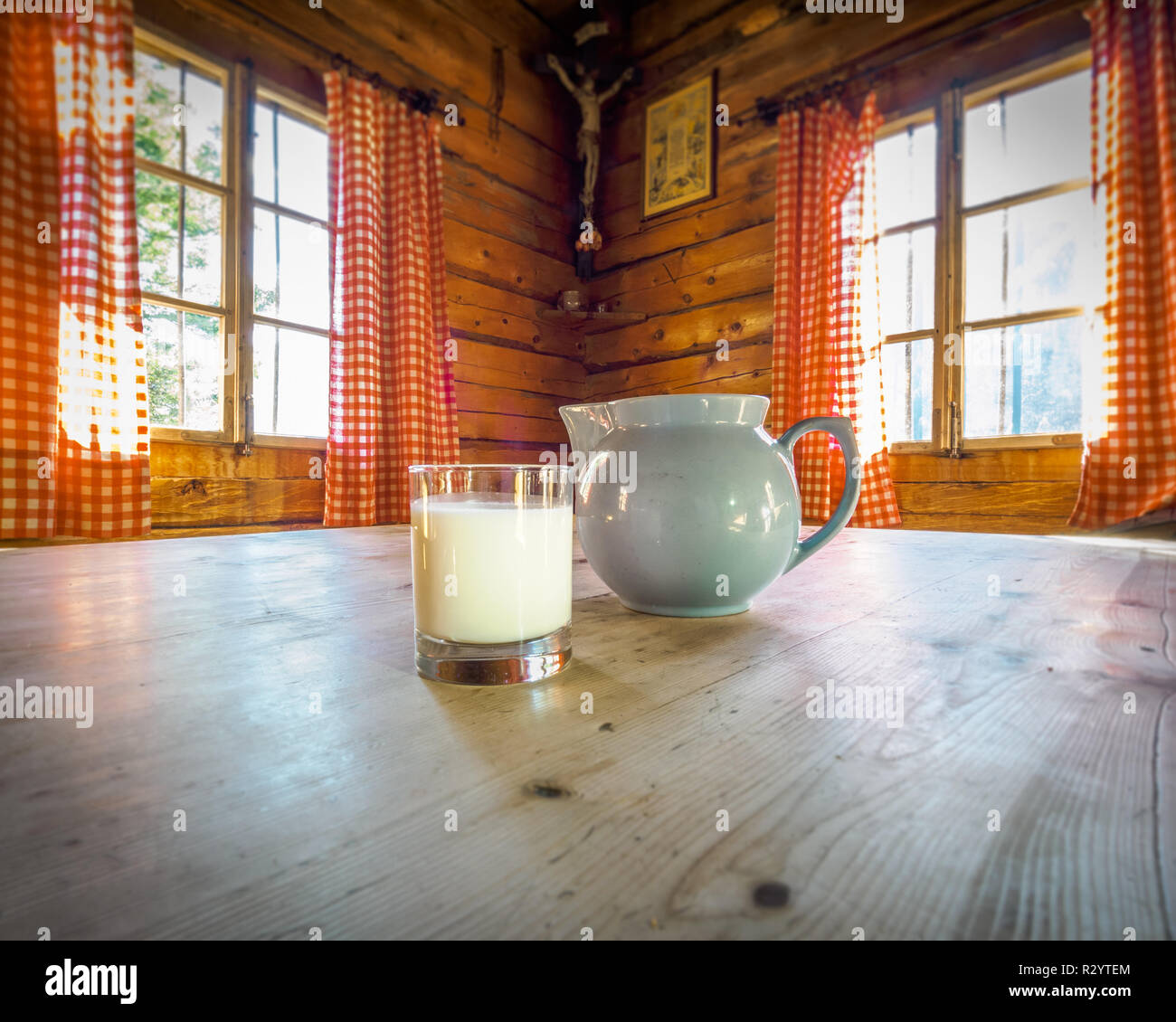 Milchkännchen und Milch in einem Glas auf dem Tisch einer alten Hütte Stockfoto