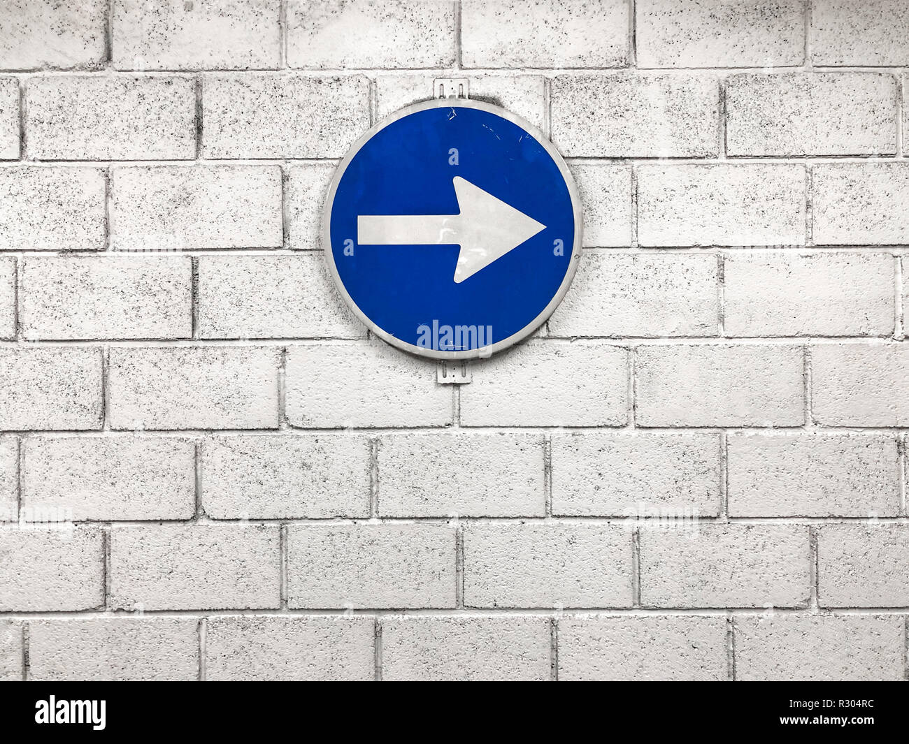 Weißer Pfeil auf blauem Schild hängen an der Wand nach rechts Richtung Stockfoto