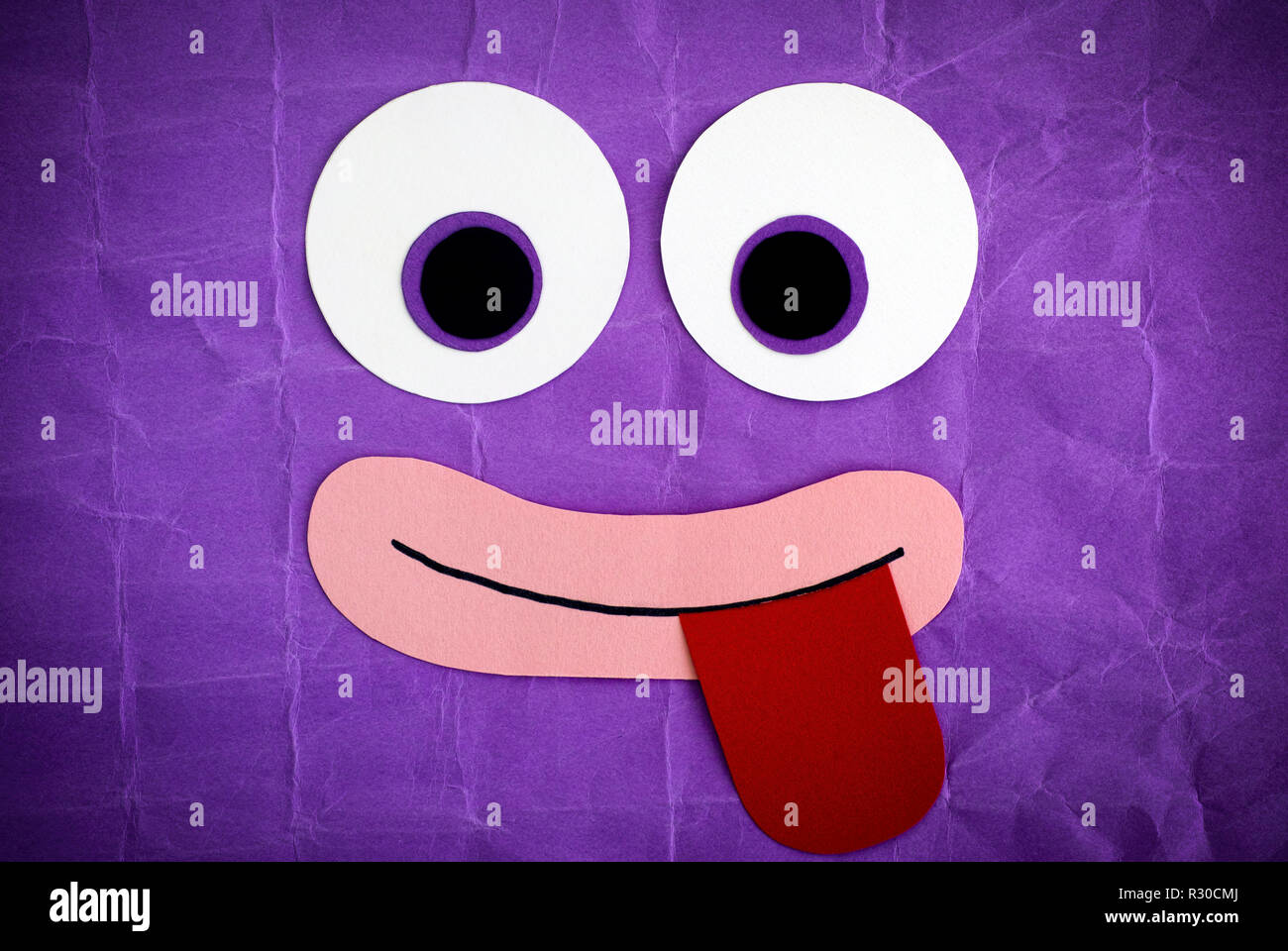 Lustiges Gesicht mit herausgestreckter Zunge heraus. Emotionale Gesicht aus Papier. Purple Background. Stockfoto