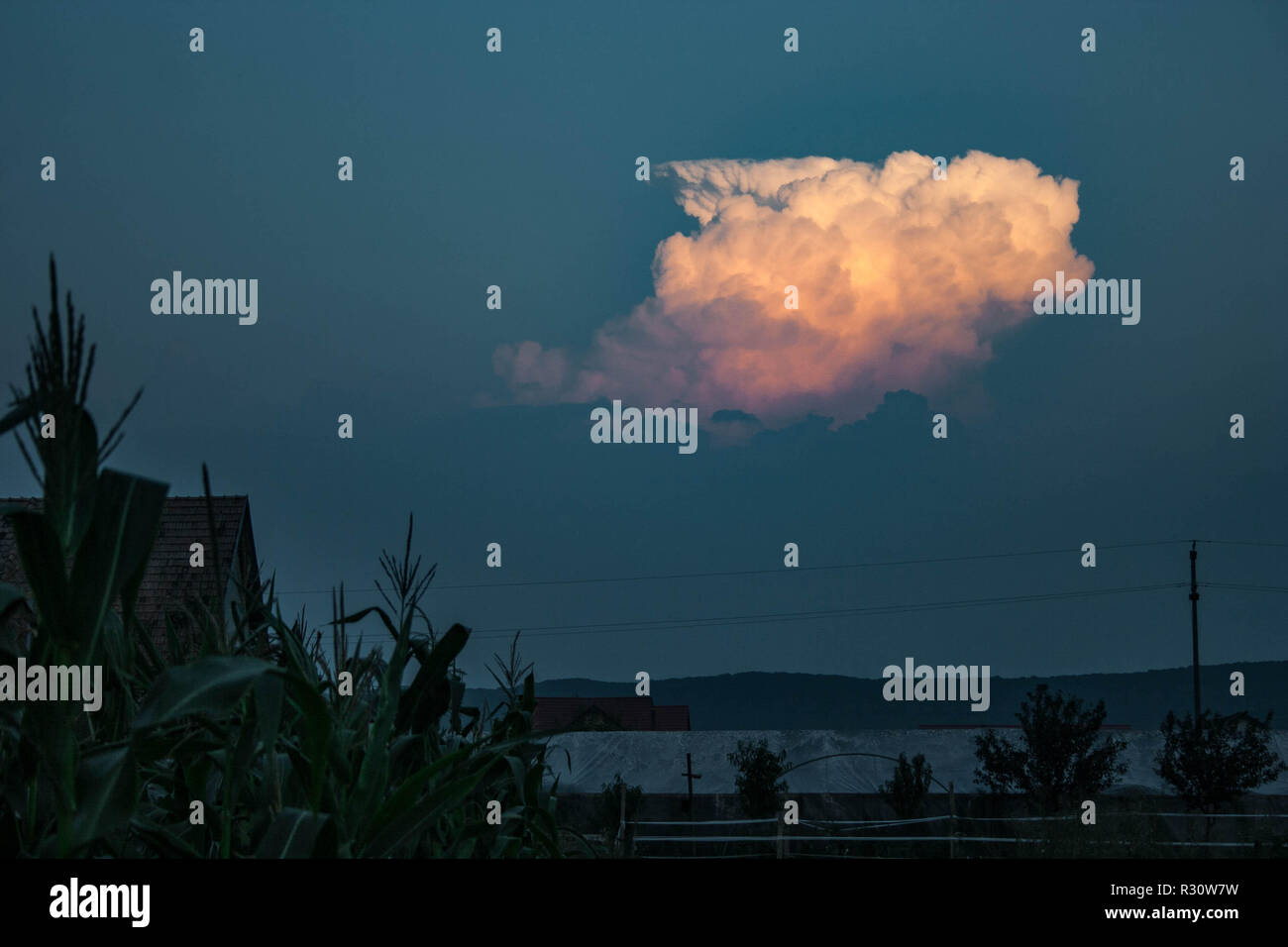 Ein Gewitter, das sich in der Dämmerung über einer trüben Schicht erhebt, beleuchtet von der untergehenden Sonne an einem Sommerabend in Transsilvanien, Rumänien Stockfoto