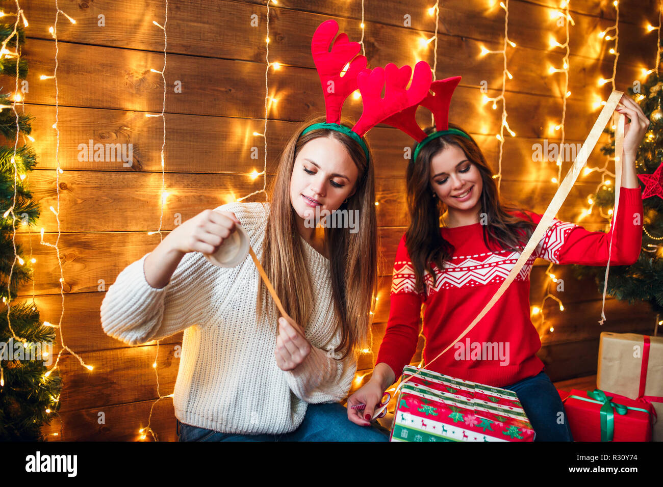 Schönen Schwestern verpacken und dekorieren Geschenk in der Nähe von  Weihnachten Baum Stockfotografie - Alamy