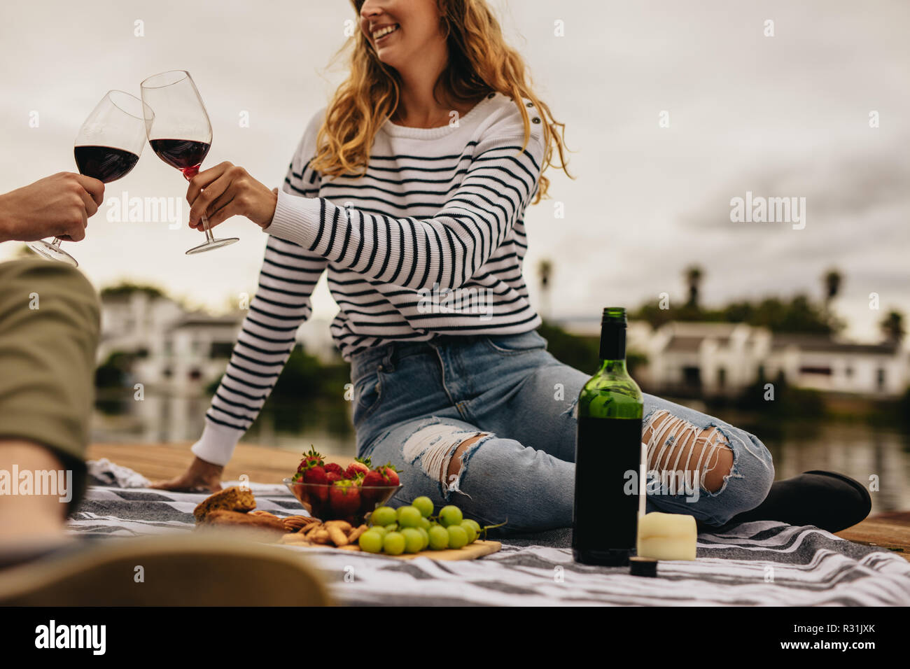 Paar auf ein Datum an einem See Essen, Snacks und Wein zu trinken. Junge Frau sitzt mit ihrem Freund Wein trinken auf ein Datum. Stockfoto