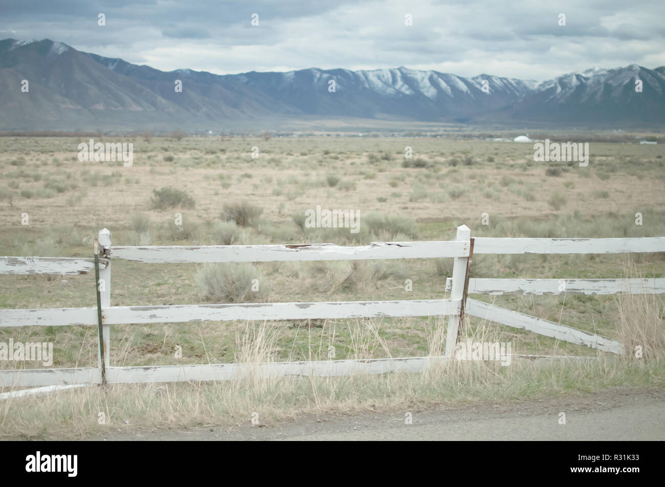 Eine gebrochene weißen Lattenzaun vor der offenen Wüste Ebene mit den Bergen dahinter in Utah. Stockfoto