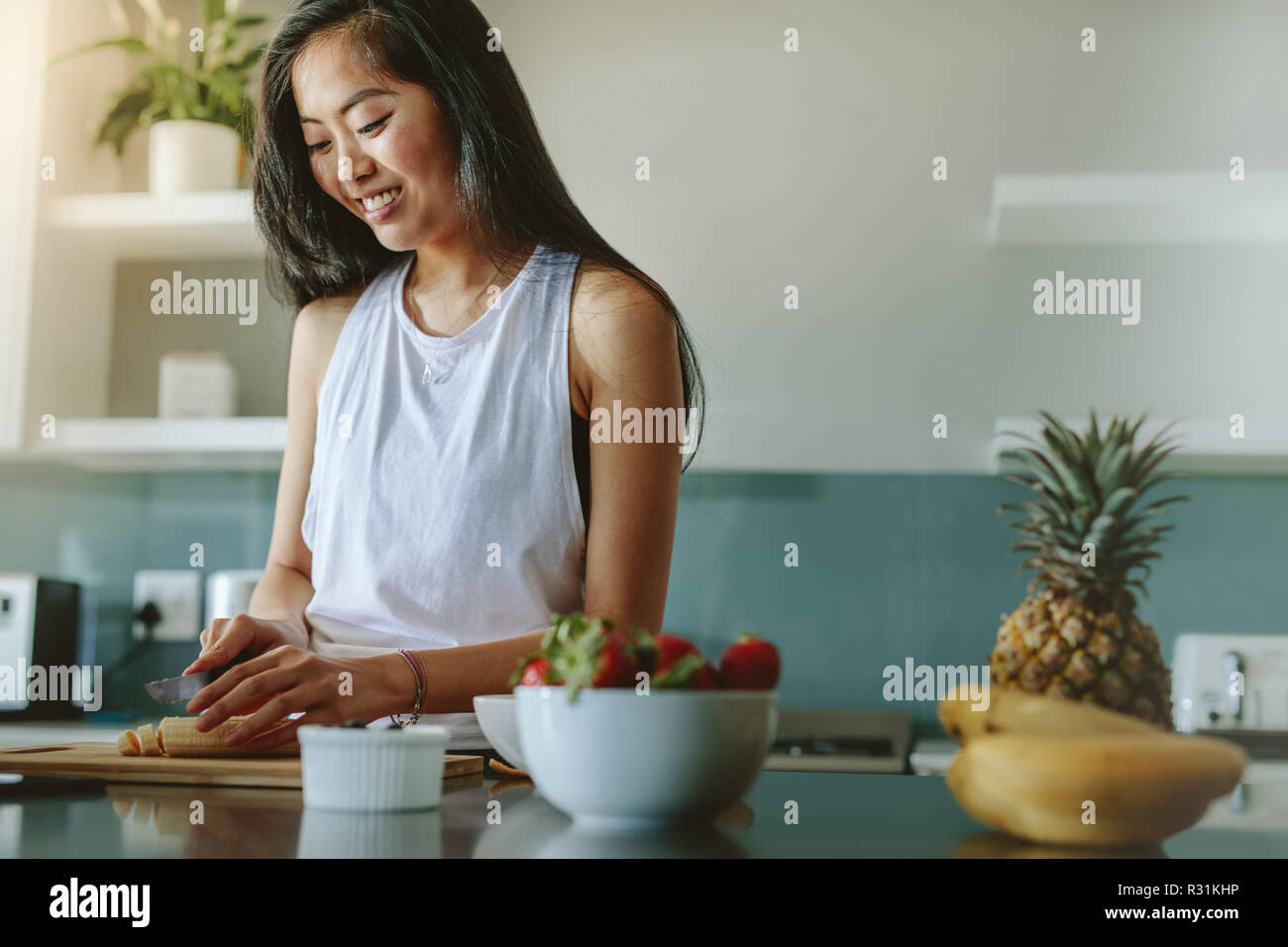 Frau vorbereiten gesunder Salat von frischen Früchten in der Küche. Weiblich, gesundes Frühstück am Morgen nach dem Training. Stockfoto