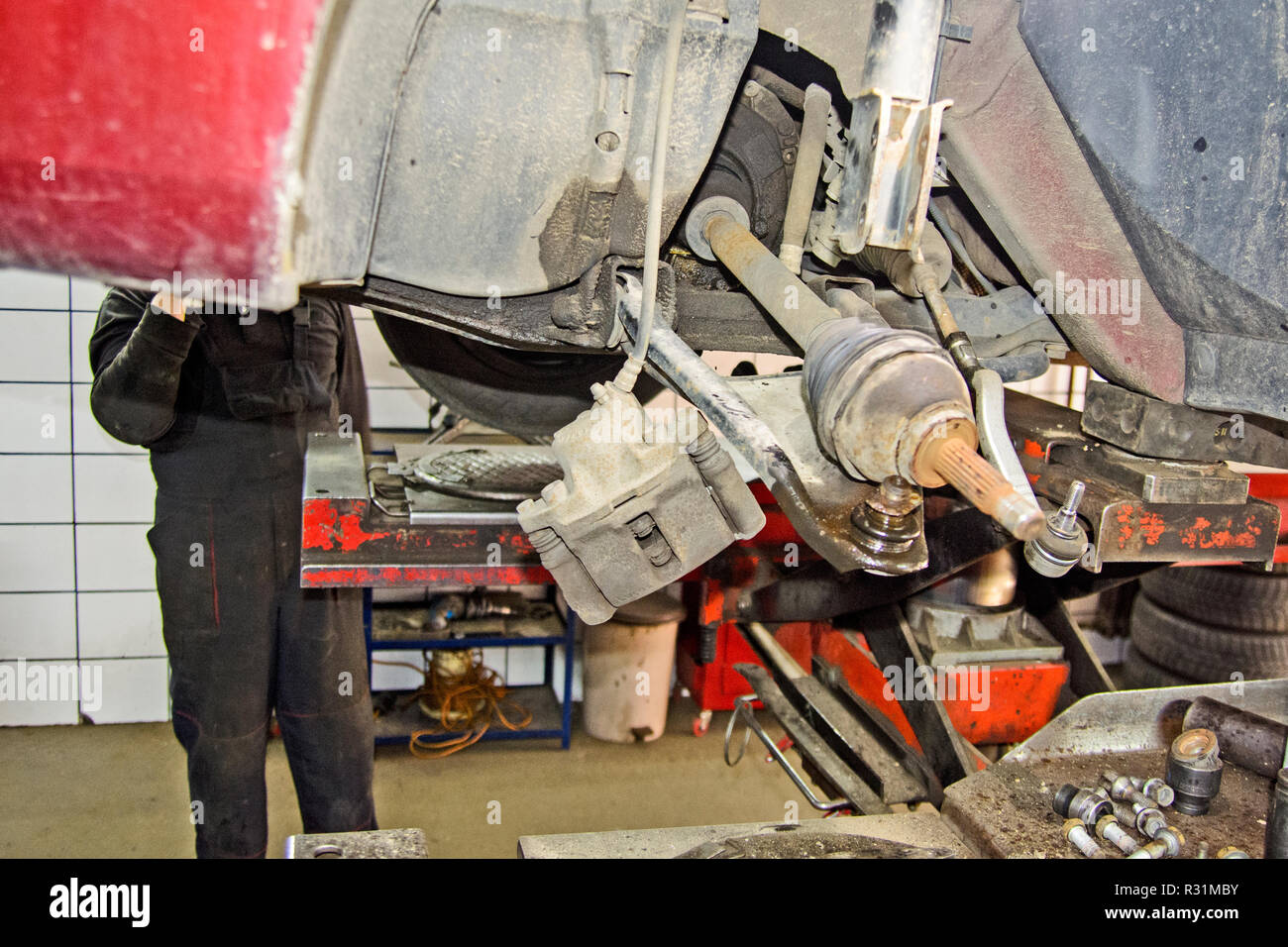Der Mechaniker in der Werkstatt ersetzt das Lager auf die Vorderachse des Wagens. Stockfoto