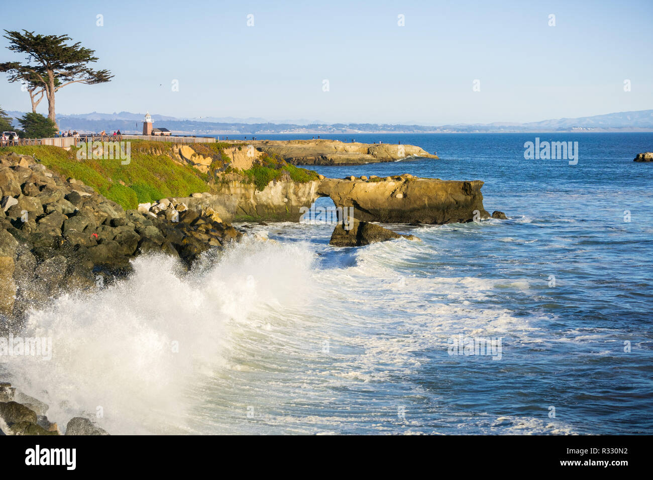 Wellen, die auf der felsigen Küste des Pazifiks; Santa Cruz Surfing Museum im Hintergrund; Kalifornien Stockfoto