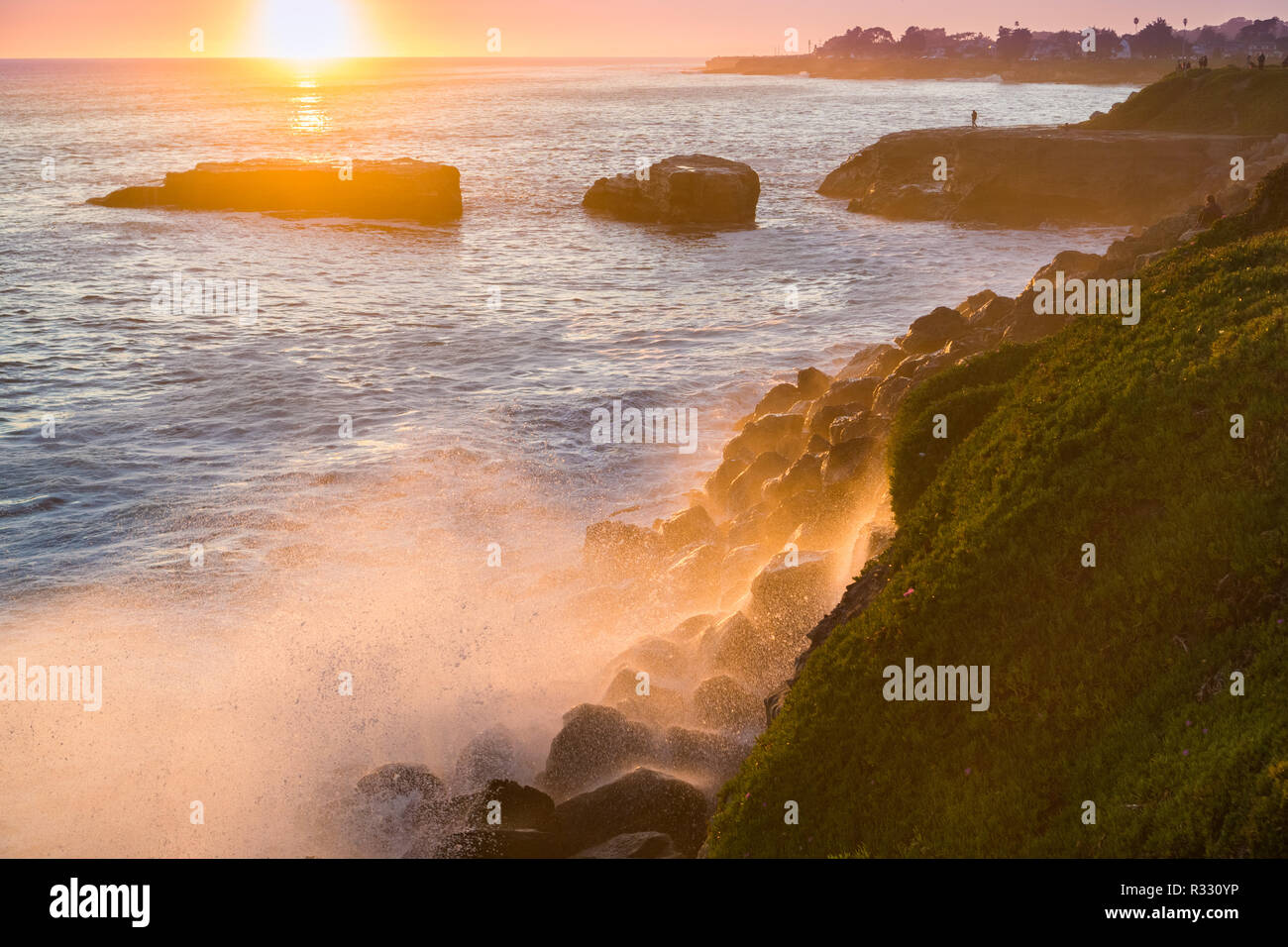 Die Wellen brechen an der felsigen Küste bei Sonnenuntergang, Santa Cruz, Kalifornien Stockfoto