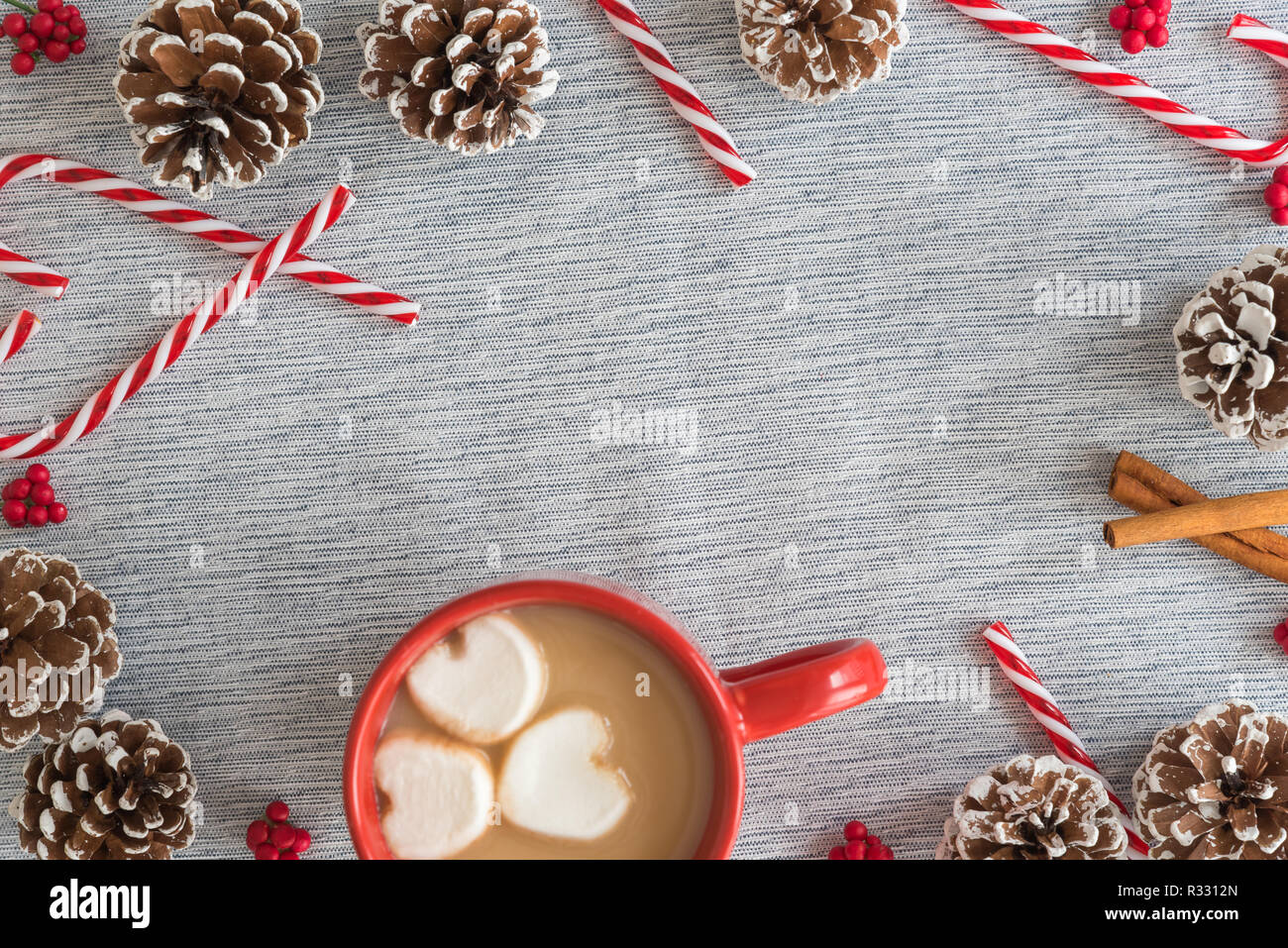 Rot Tasse heiße Schokolade und Marshmallows in Herzform mit Rahmen von Zuckerstangen und kiefernzapfen Stockfoto