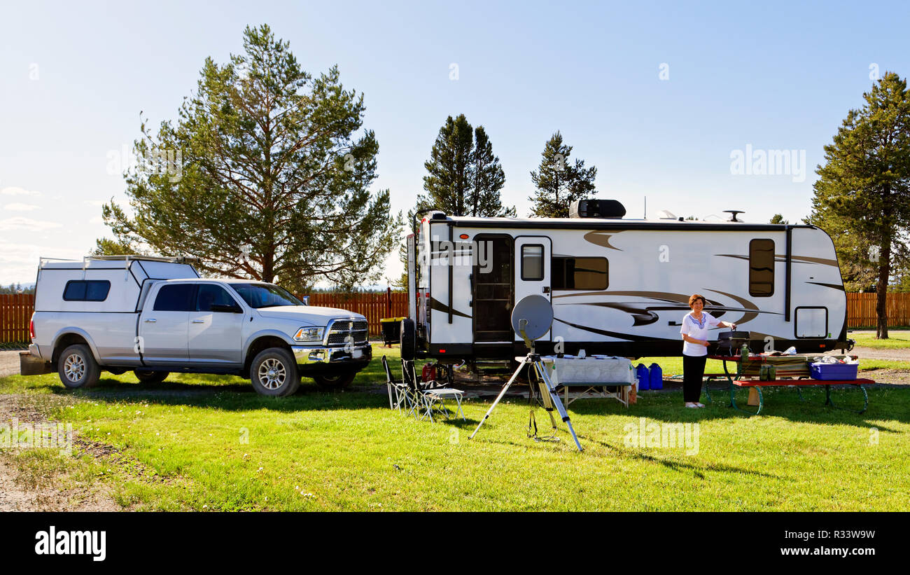 42,881.02545 Frau camper Reisenden stehen die RV camp Trailer und 3/4 Tonne Pickup truck Zugfahrzeug, in schön gemäht grünes Gras RV Park mit Bäumen Stockfoto
