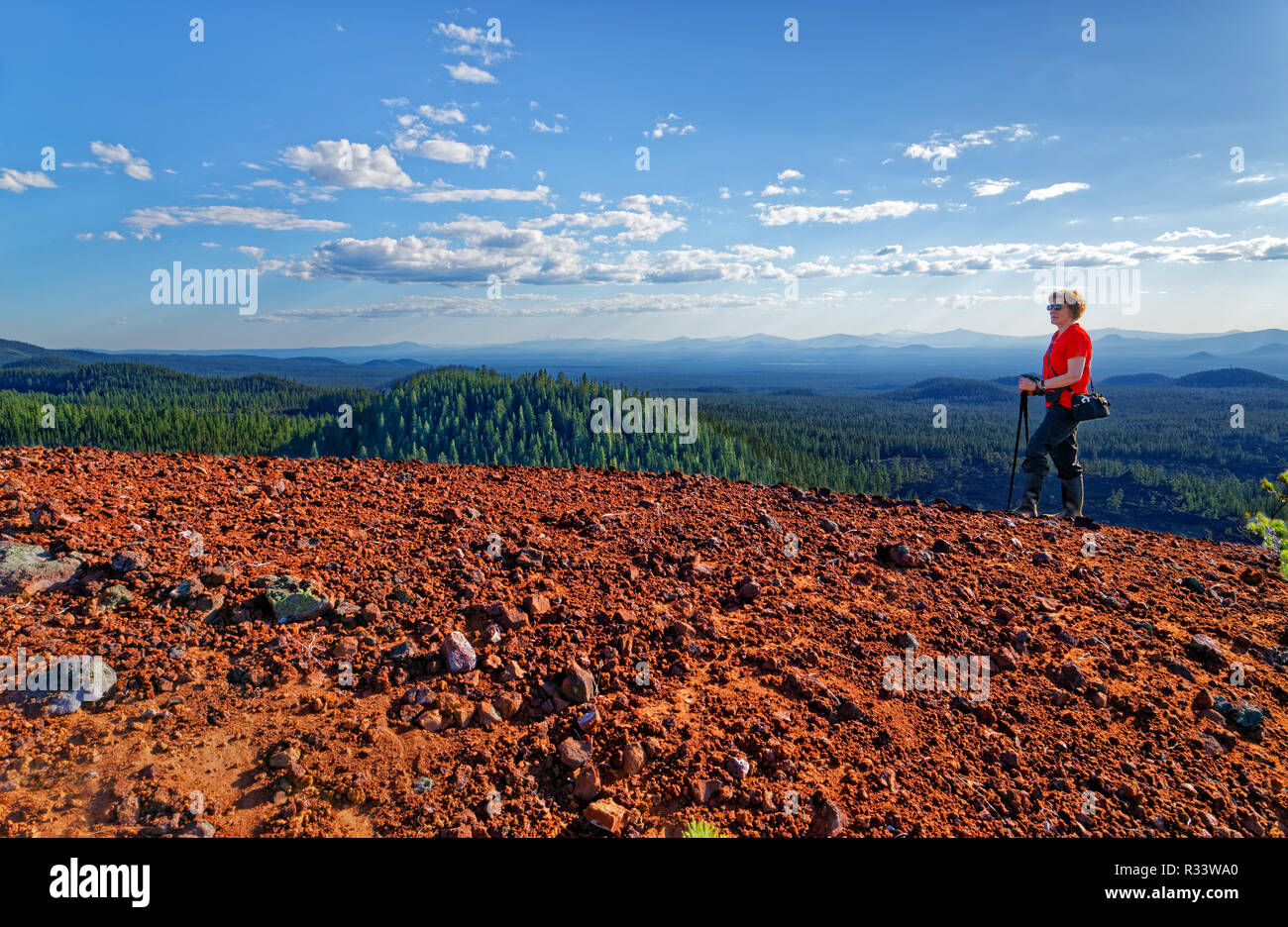 42,882.02712 Frau wandern oben weiten schönen vulkanischen rot Schlackenkegel, Bäume rolling hills & Nadelwäldern in der Ferne, blaue Himmel Weisse Wolken Stockfoto