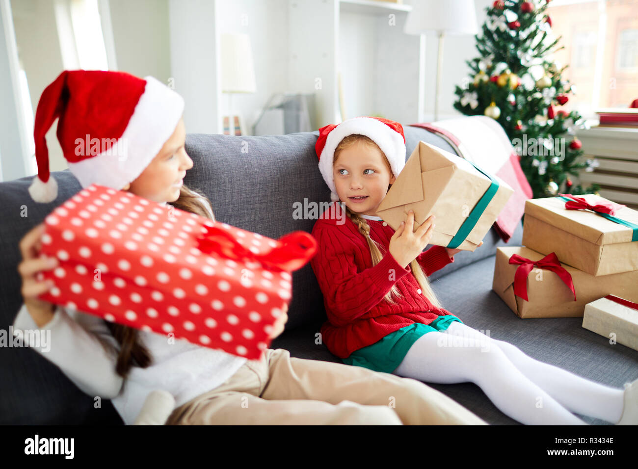 Cute Santa Geschwister schütteln giftboxes beim Versuchen zu erraten, was innen ist Stockfoto