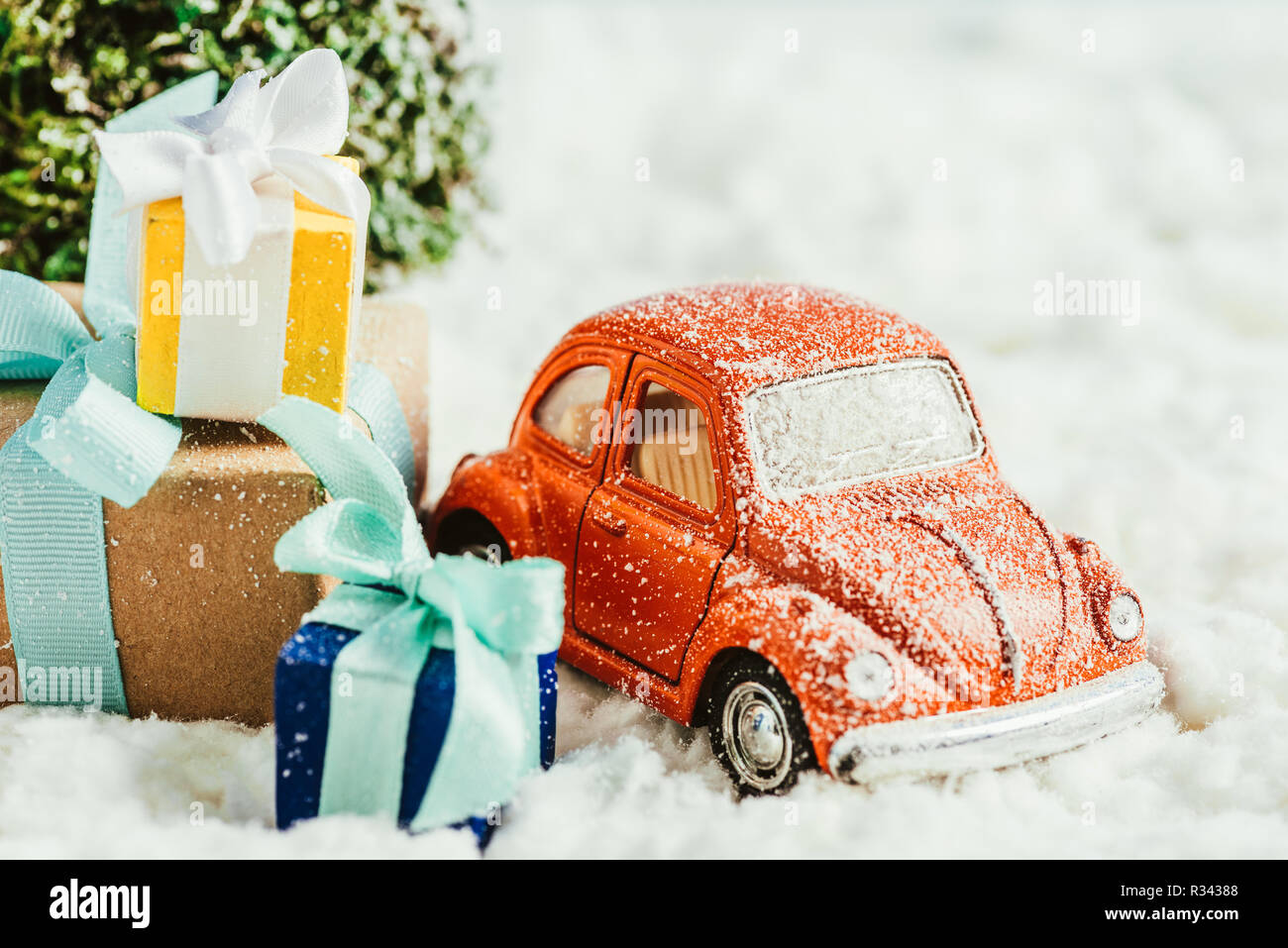 Nahaufnahme der Spielzeugauto mit Geschenken und Weihnachtsbaum stehen auf Schnee aus Baumwolle Stockfoto