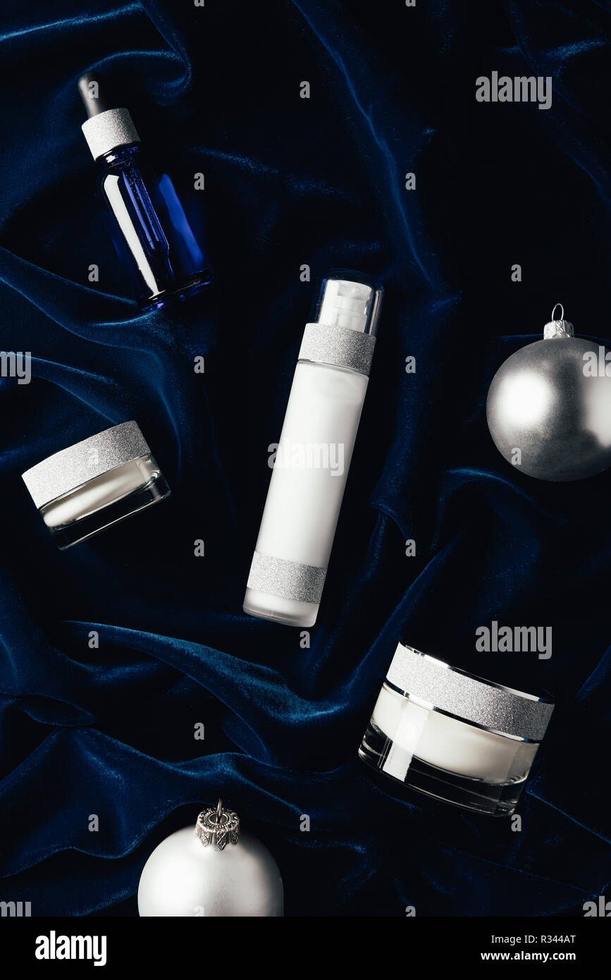 Flach mit beauty Creme, Serum, Lotion und Silber Weihnachten Kugeln auf samtene Oberfläche Stockfoto