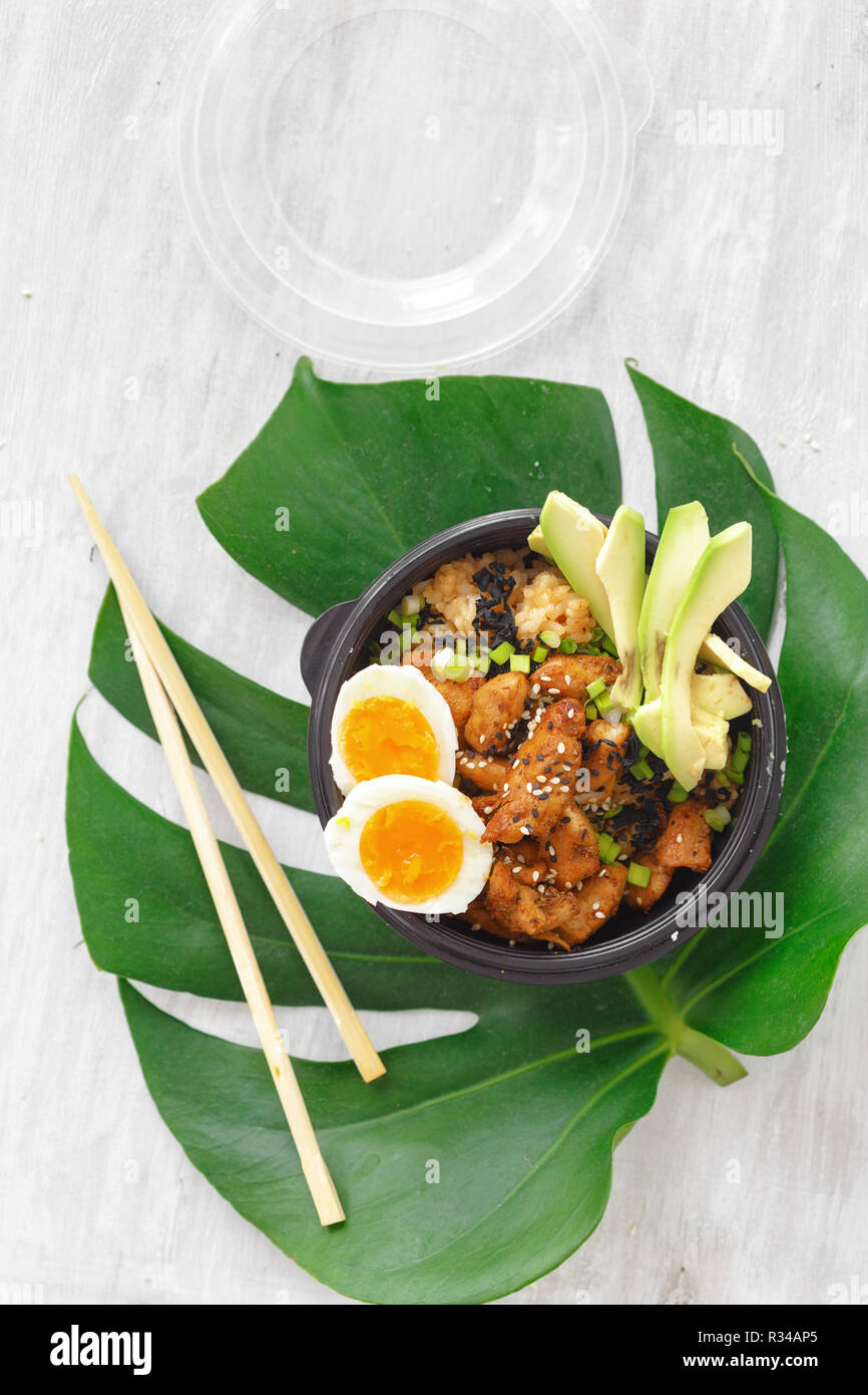 Asian take away Konzept. Zwei poke Schüssel mit gebratener Reis, Hühnerfleisch, Avocado und Eier in der Box auf woocen Tabelle Ansicht von oben Stockfoto