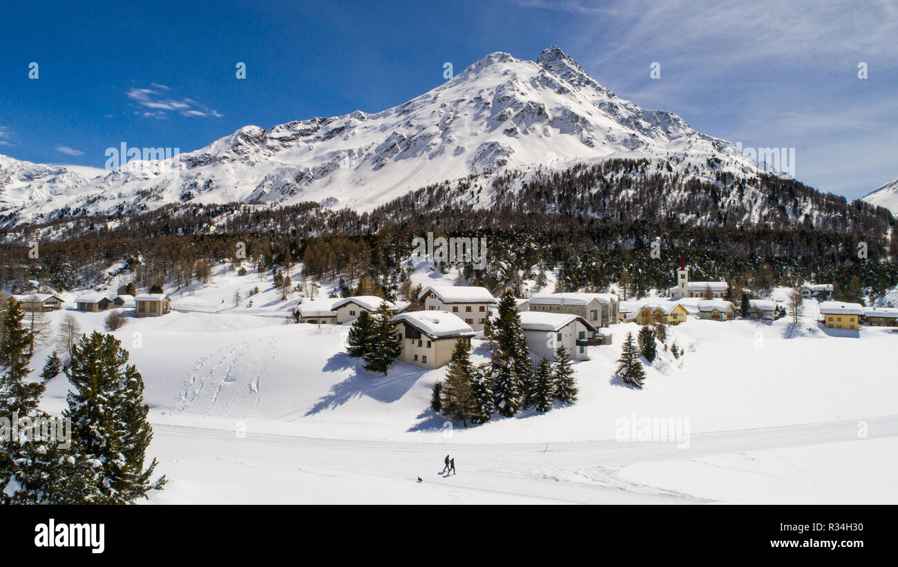 Kleines Dorf und Wald mit Schnee bedeckt. Engadin in den Schweizer Alpen. Luftaufnahme Stockfoto