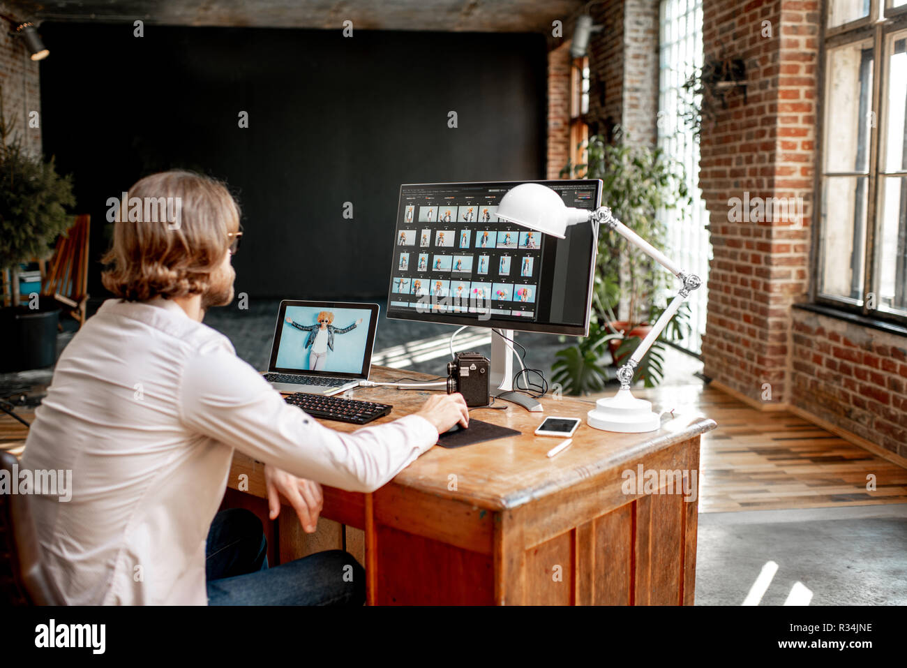 Junge männliche Fotografen arbeiten mit Porträts der Frau am Arbeitsplatz sitzen mit zwei Computern im Studio Stockfoto