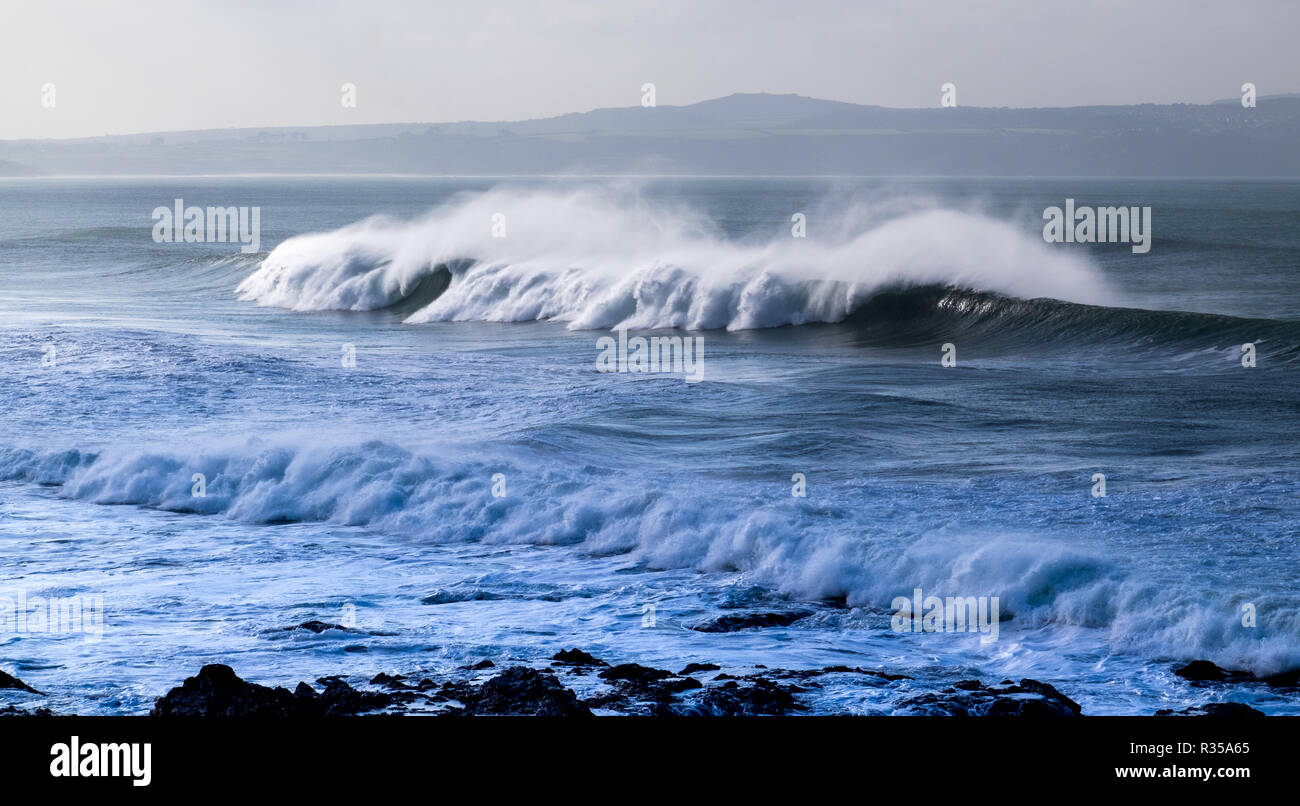 Einzigen großen brechende Welle auf den Strand rollen mit dem starken Wind das Spray nach hinten bläst einem fliegenden Nebel auf Godrevy, Cornwall zu erstellen. Stockfoto