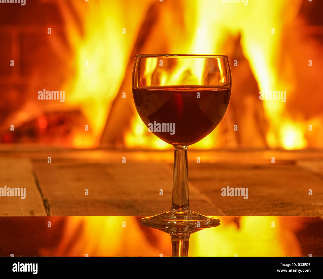 Glas Rotwein gegen gemütlichen Kamin Hintergrund, winter Urlaub, Winter Urlaub, Landhaus, horizontal. Stockfoto