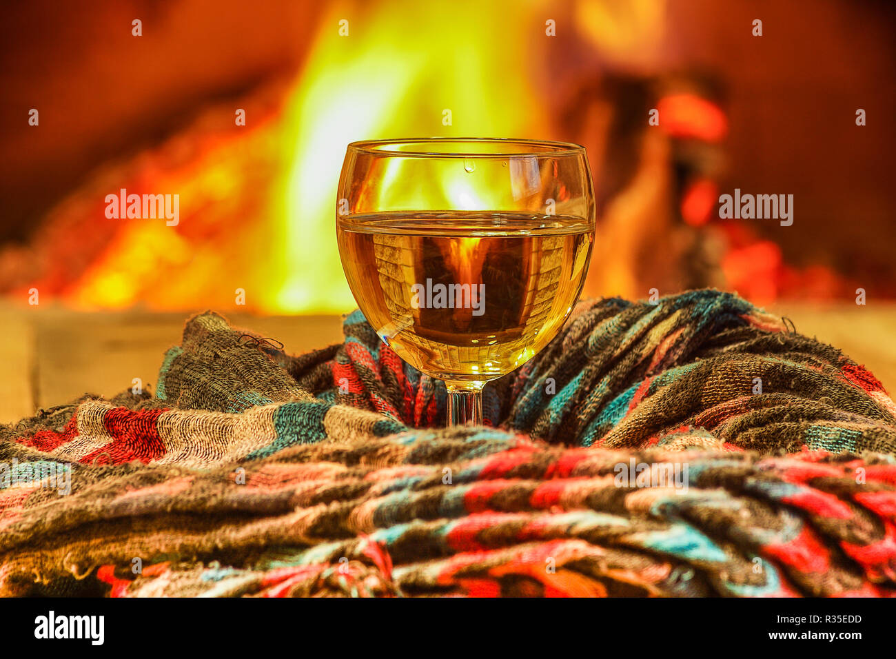 Glas Weißwein gegen gemütlichen Kamin Hintergrund, winter Urlaub, Winter Urlaub, Landhaus, horizontal. Stockfoto