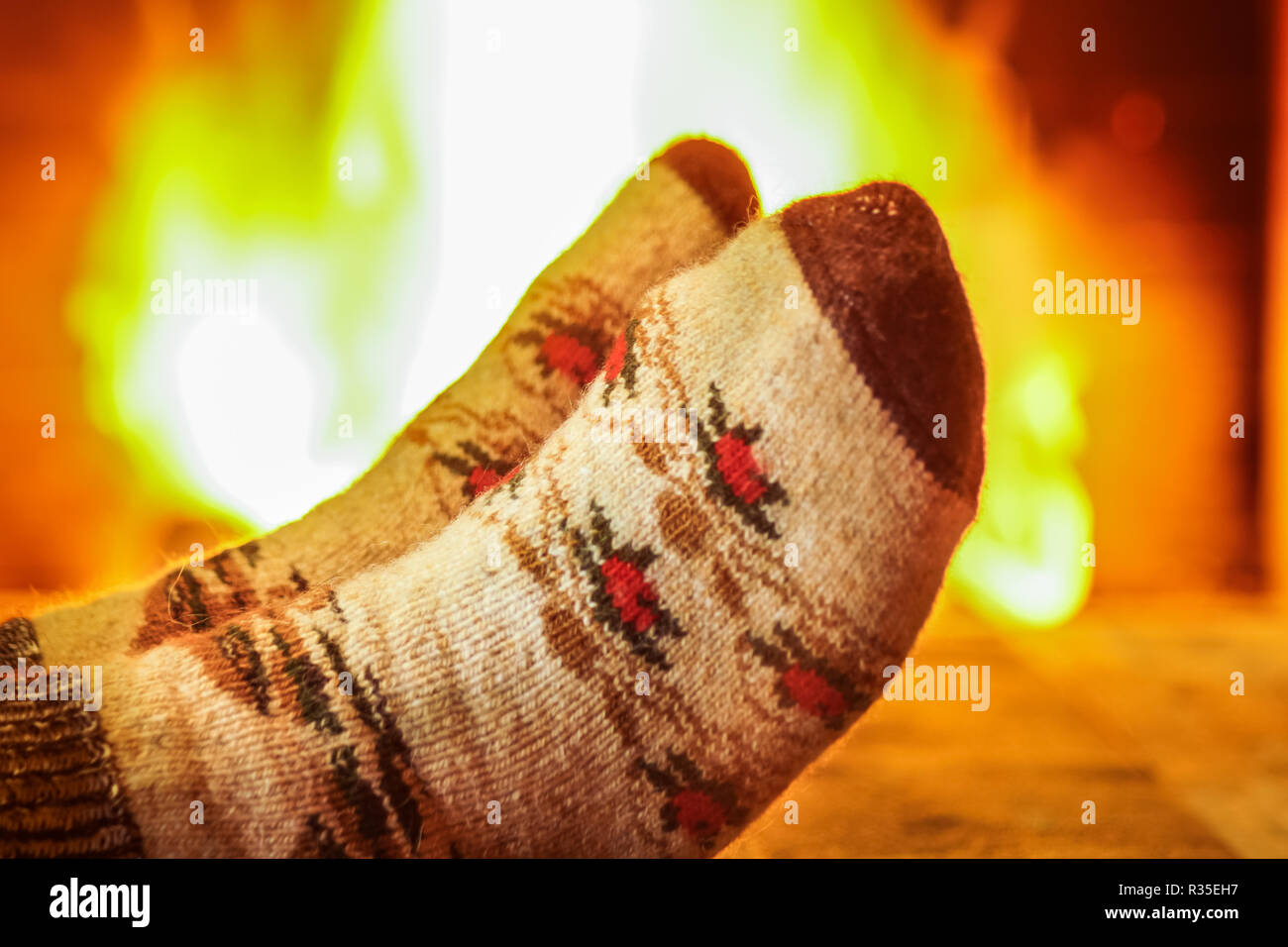 Der Mann Füße in die Wolle für die Socken, gegen den gemütlichen Kamin Hintergrund, im Herrenhaus, Winter Urlaub. Stockfoto