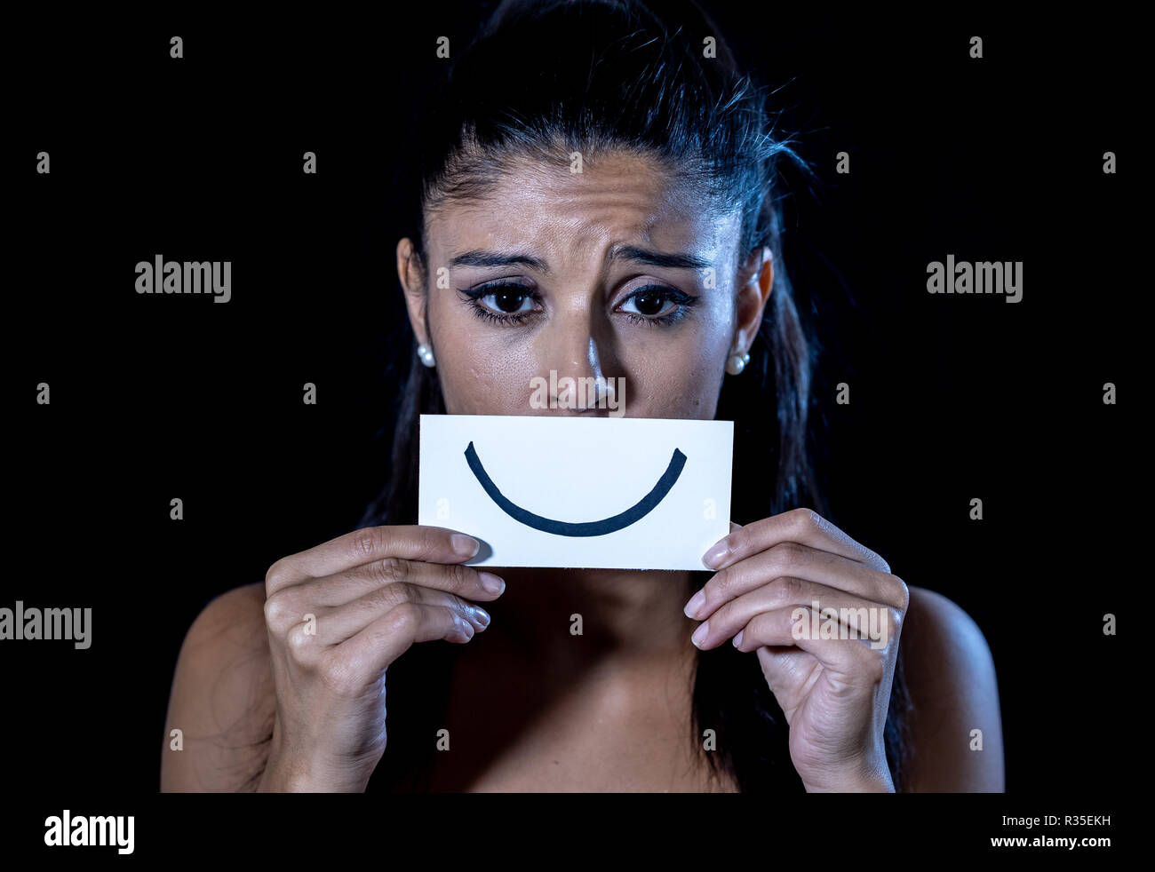 Dramatische Nahaufnahme Portrait von traurige Frau ihre Depression verstecken mit Lächeln auf Papier in der menschlichen Emotion leiden in der Stille depression Konzept iso lackiert Stockfoto