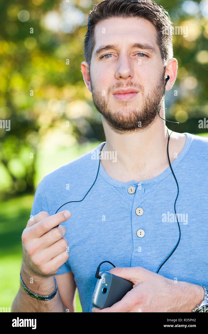 Junger Mann im Park Musik hören Stockfoto