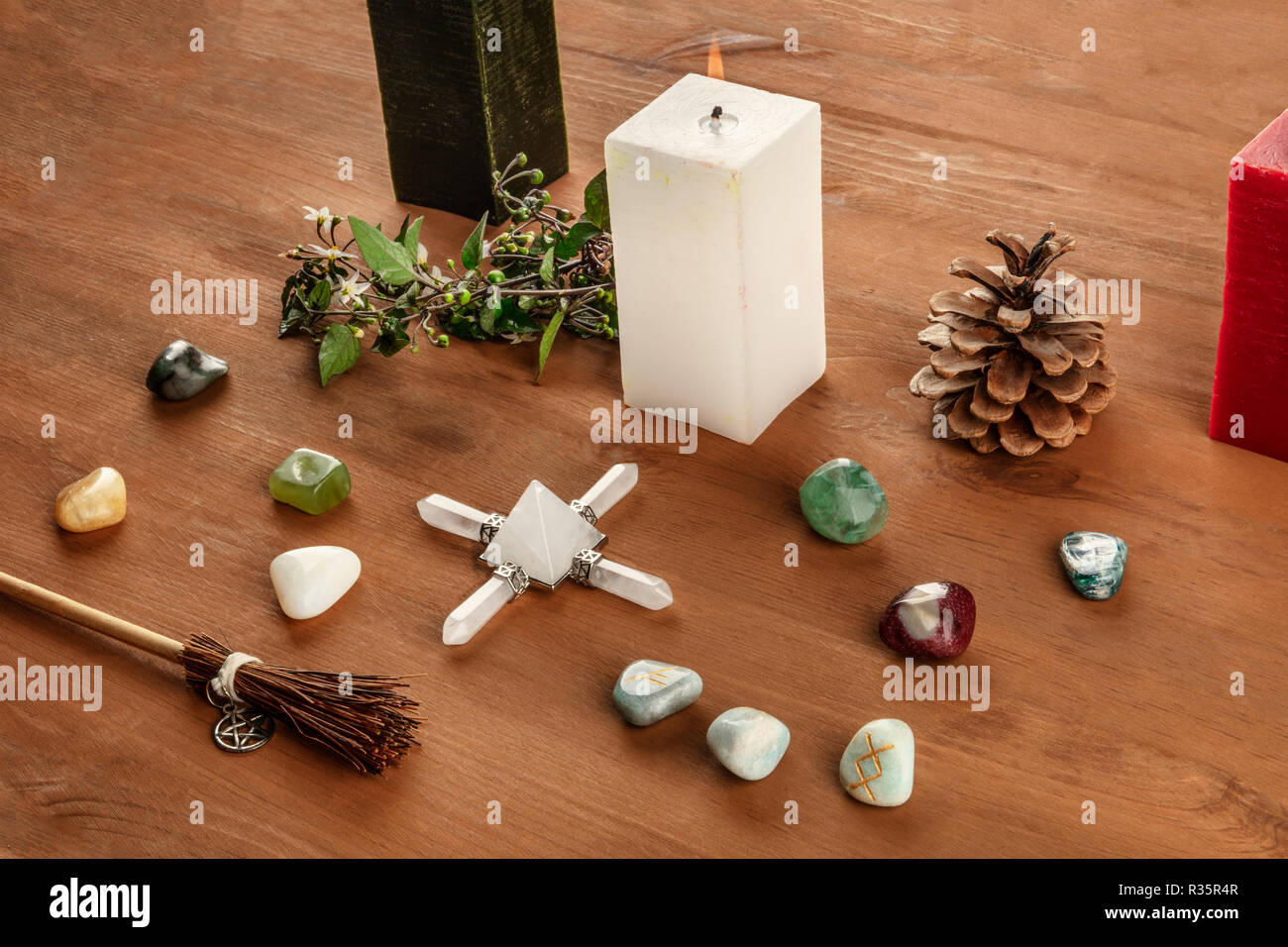 Die Hexerei. Eine Wicca Altar mit Kerzen, Kristall Steinen, und Runen, mit einem kleinen Besen mit einem Pentagramm, auf einem dunklen Holzmöbeln im Landhausstil Hintergrund Stockfoto