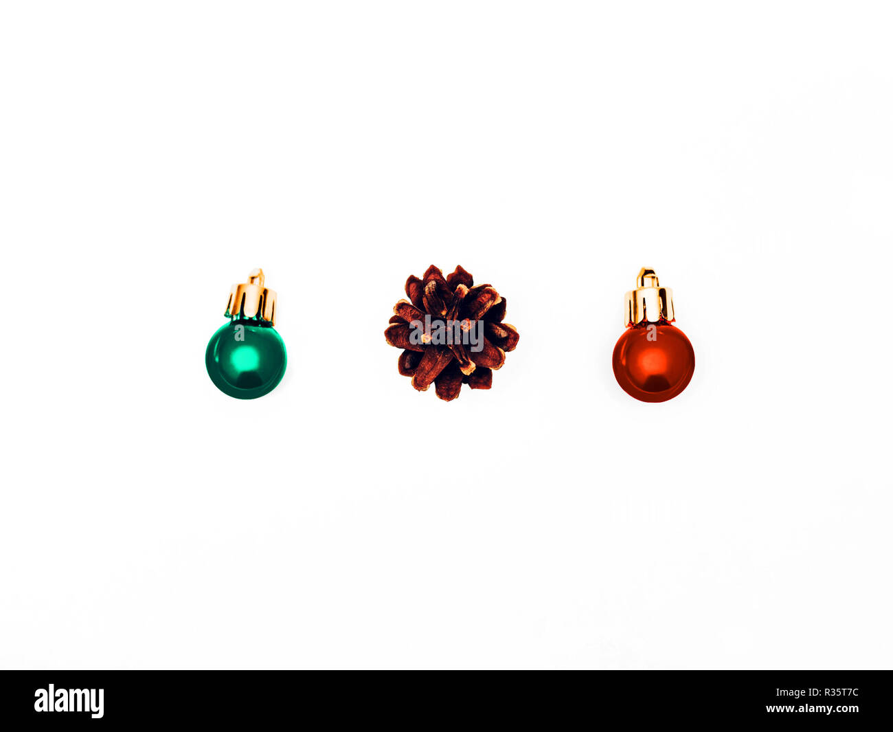 Weihnachten Kugeln in Flach isoliert Foto zwei kleine bunte dekorative Kugeln und einem Pinecone liegen in einer Reihe auf weißem Hintergrund Stockfoto