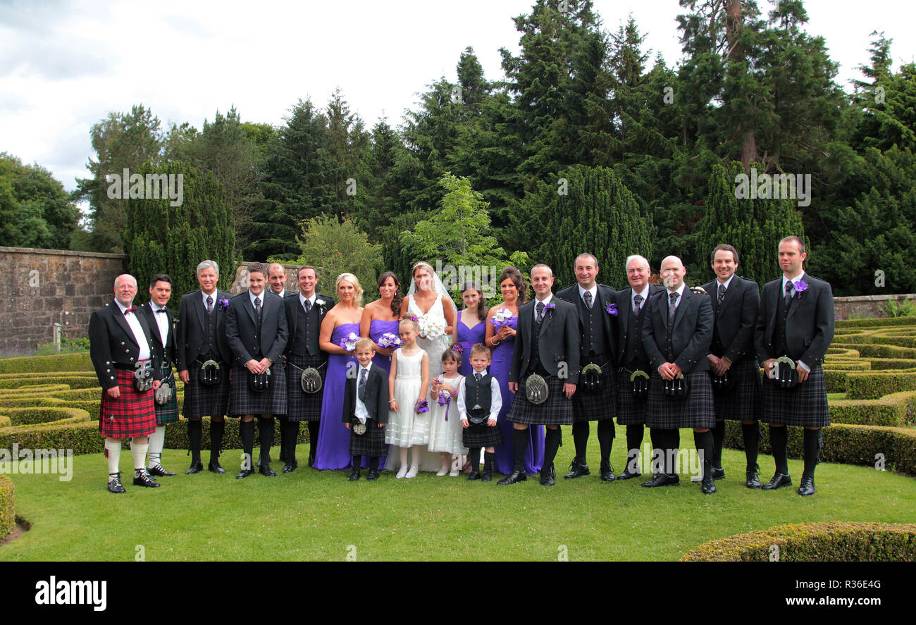Die Braut und der Bräutigam und die Hochzeitsgesellschaft, mit den Männern in der traditionellen Highland dress von tartan und Kilts, für ein Foto nur nach der Zeremonie in Schottland dar. Stockfoto