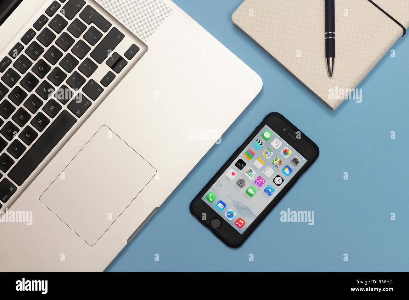 Laptop, Smartphone und eine Notiz Buch auf einem blauen Schreibtisch, flach. Stockfoto